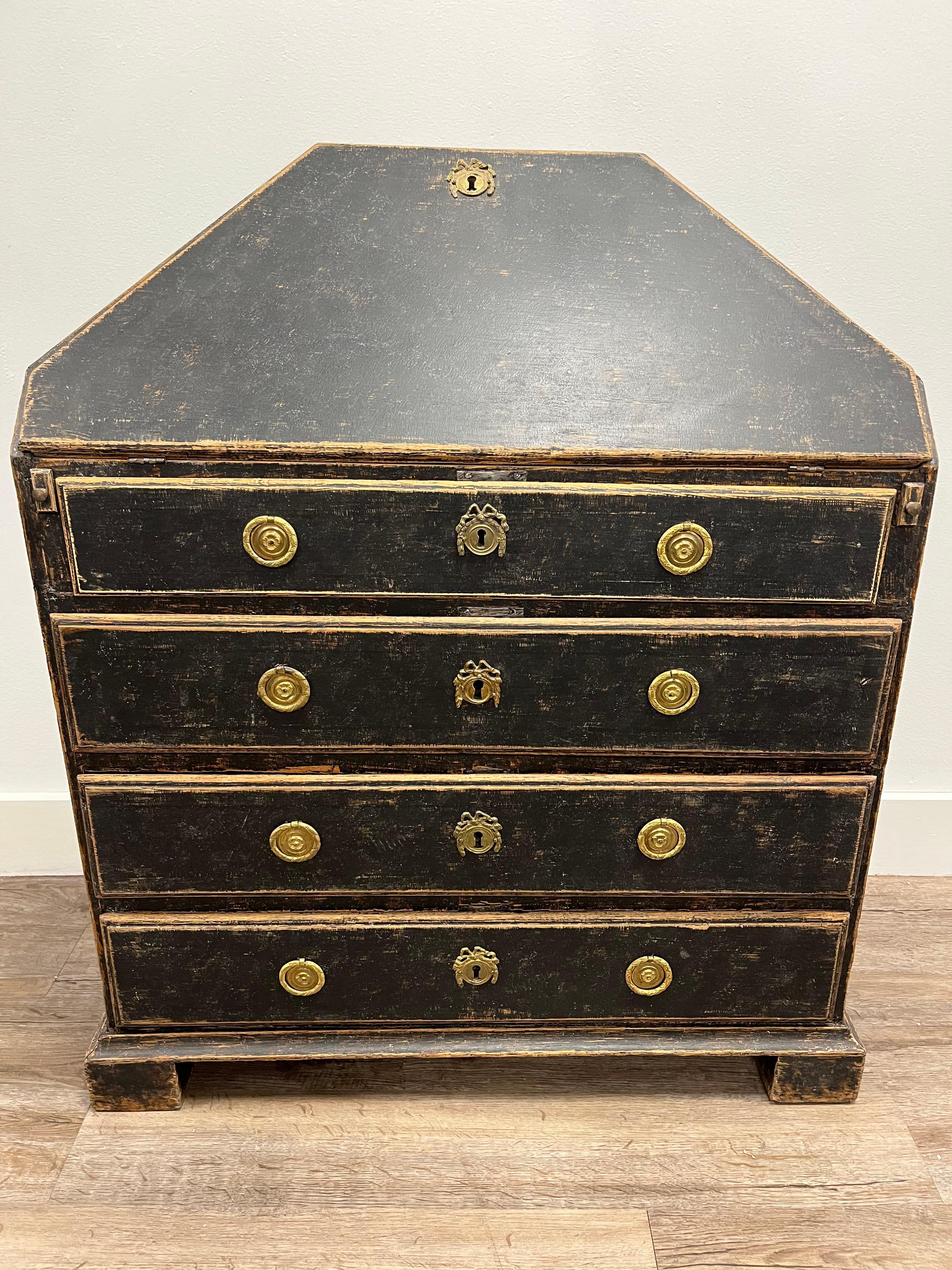 An unusual trapezoid-shaped Swedish Gustavian slant front desk. Front opens to reveal an ample work surface with six cascading drawers sitting atop one full size drawer. All drawers with petite brass pulls. One quaint cubby with ornate scrolling