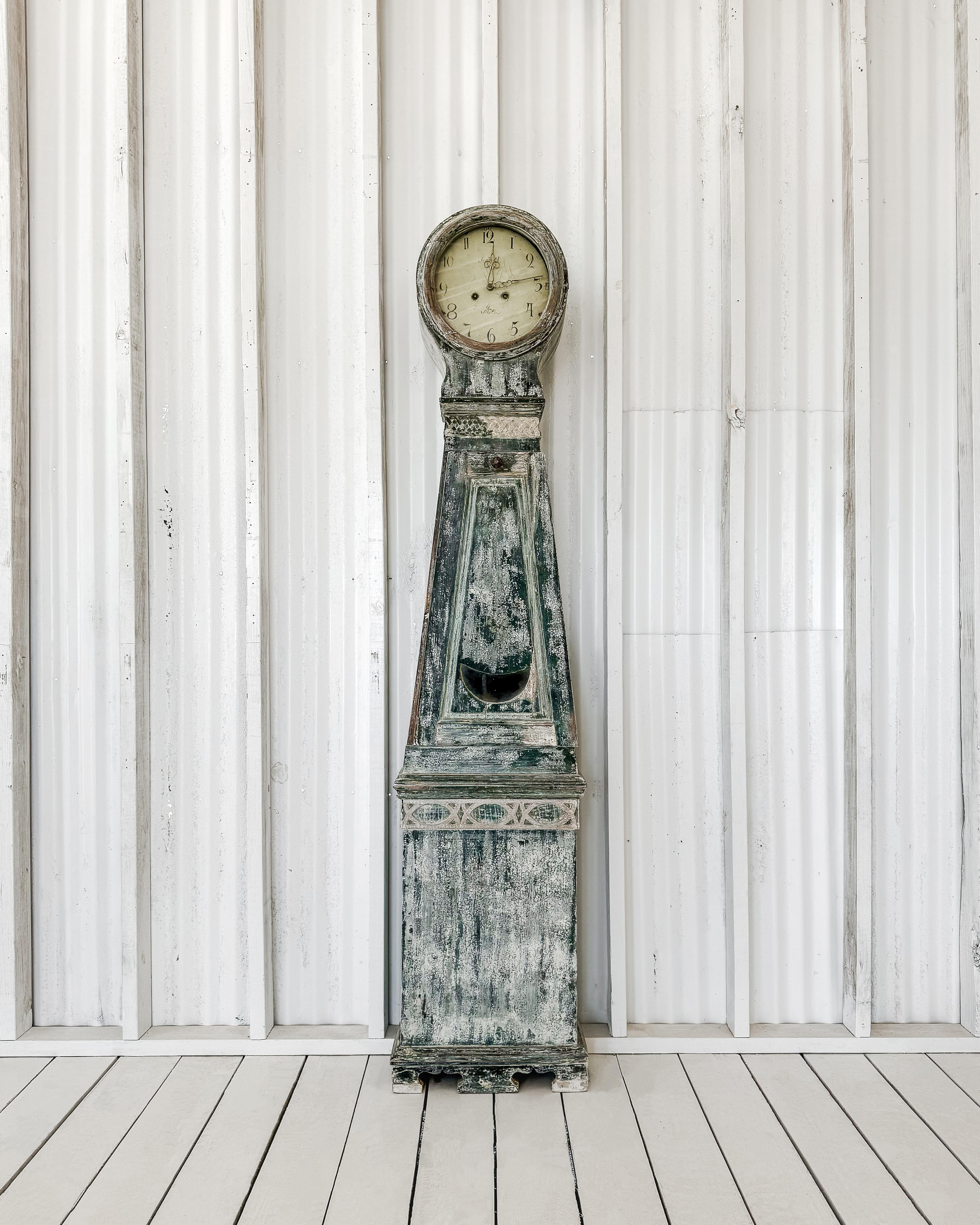 An exquisite Swedish tall case clock boasting a rounded crown and clean lines, complemented by a dry-scraped finish. The clock retains its original blue-green and alabaster paint with delicate touches of 