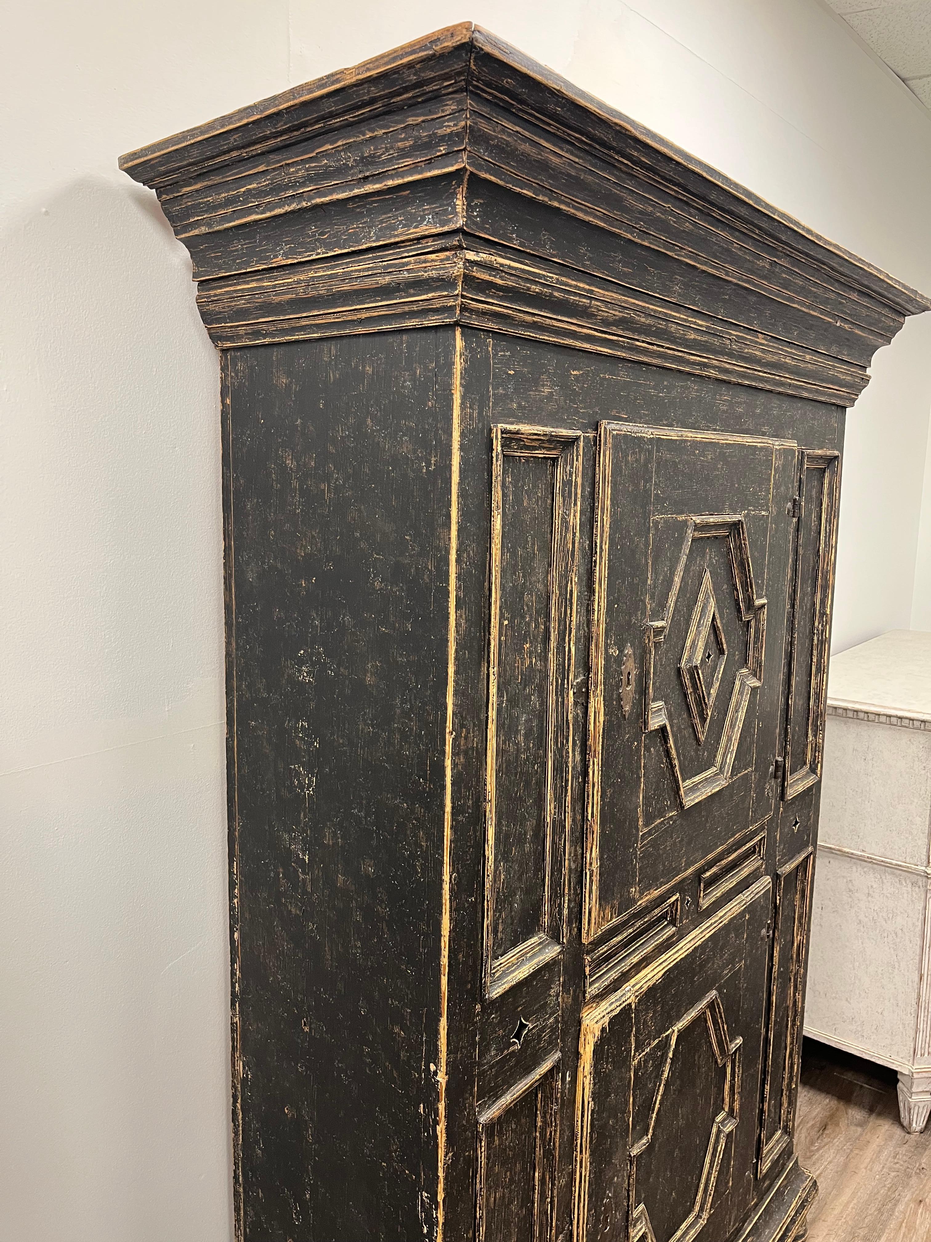 Armadio svedese tardo-barocco con cornice a frontone sporgente, intricati pannelli intagliati e incassati sul fronte e sulle porte. Quattro piccoli intagli a forma di diamante decorano la parte anteriore. Le ante si aprono per rivelare un ampio