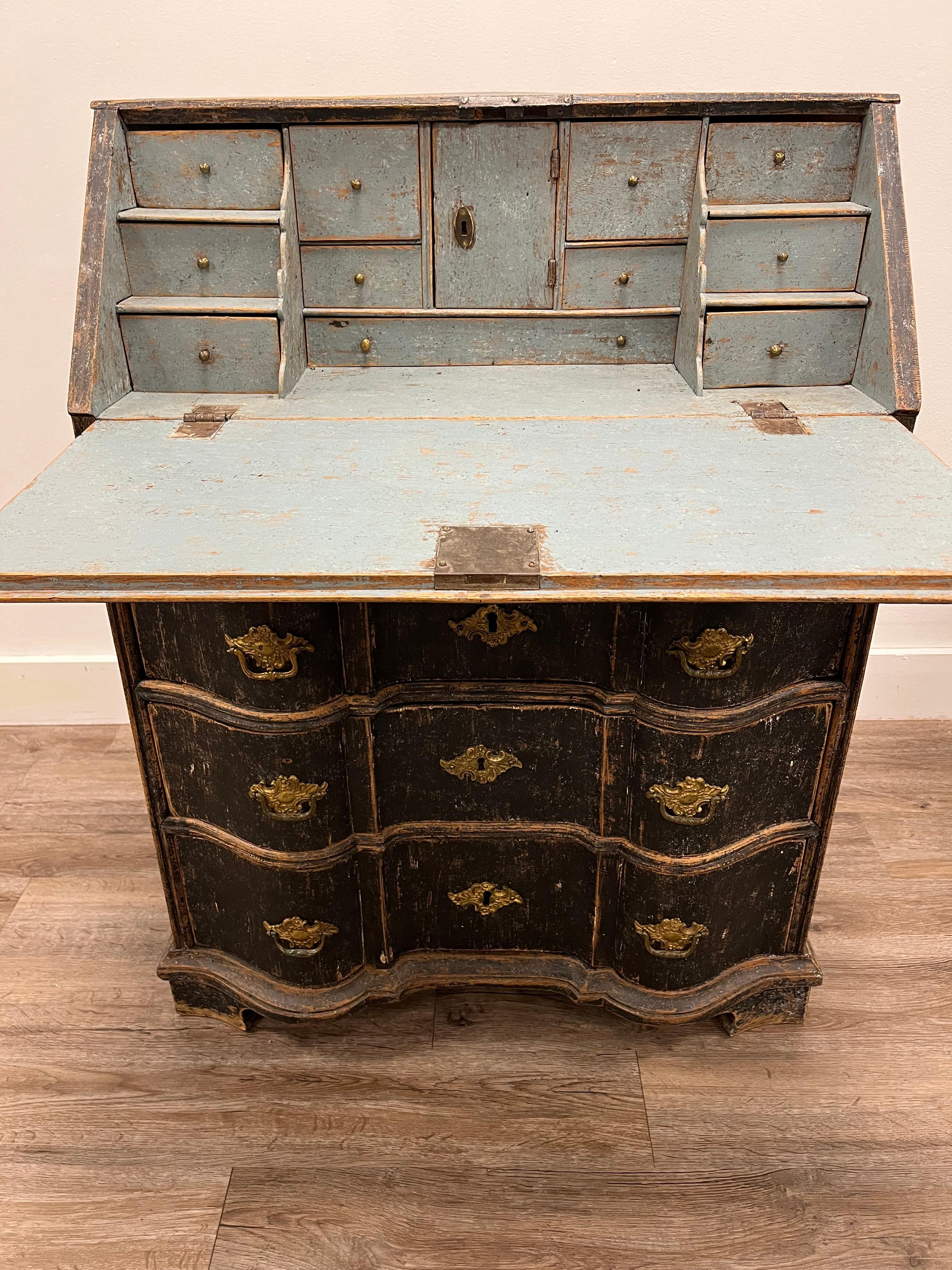 An unusual Swedish Rococo slant front corner desk. Desktop opens to reveal an ample working surface, ten small drawers with brass knobs and a locking cubby door. Interior tastefully repainted in pale blue. Desk has one smalls and three intricately