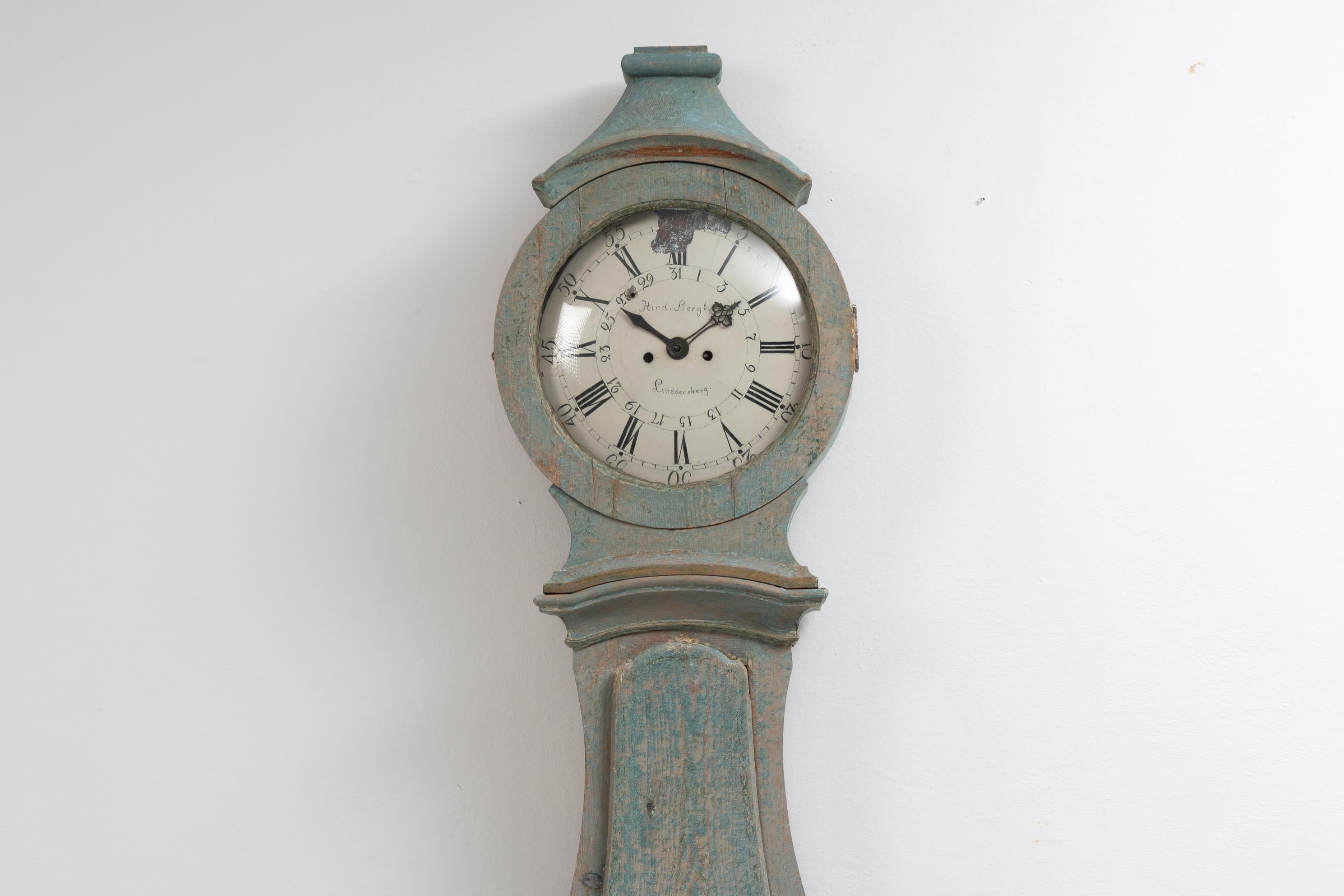 Swedish long case clock from Mälardalen, close to Stockholm. The clock is from around 1790 and the case has the classic rococo shape. The surface of the clock has been scraped to show the original first layer of light blue paint. An unusual detail