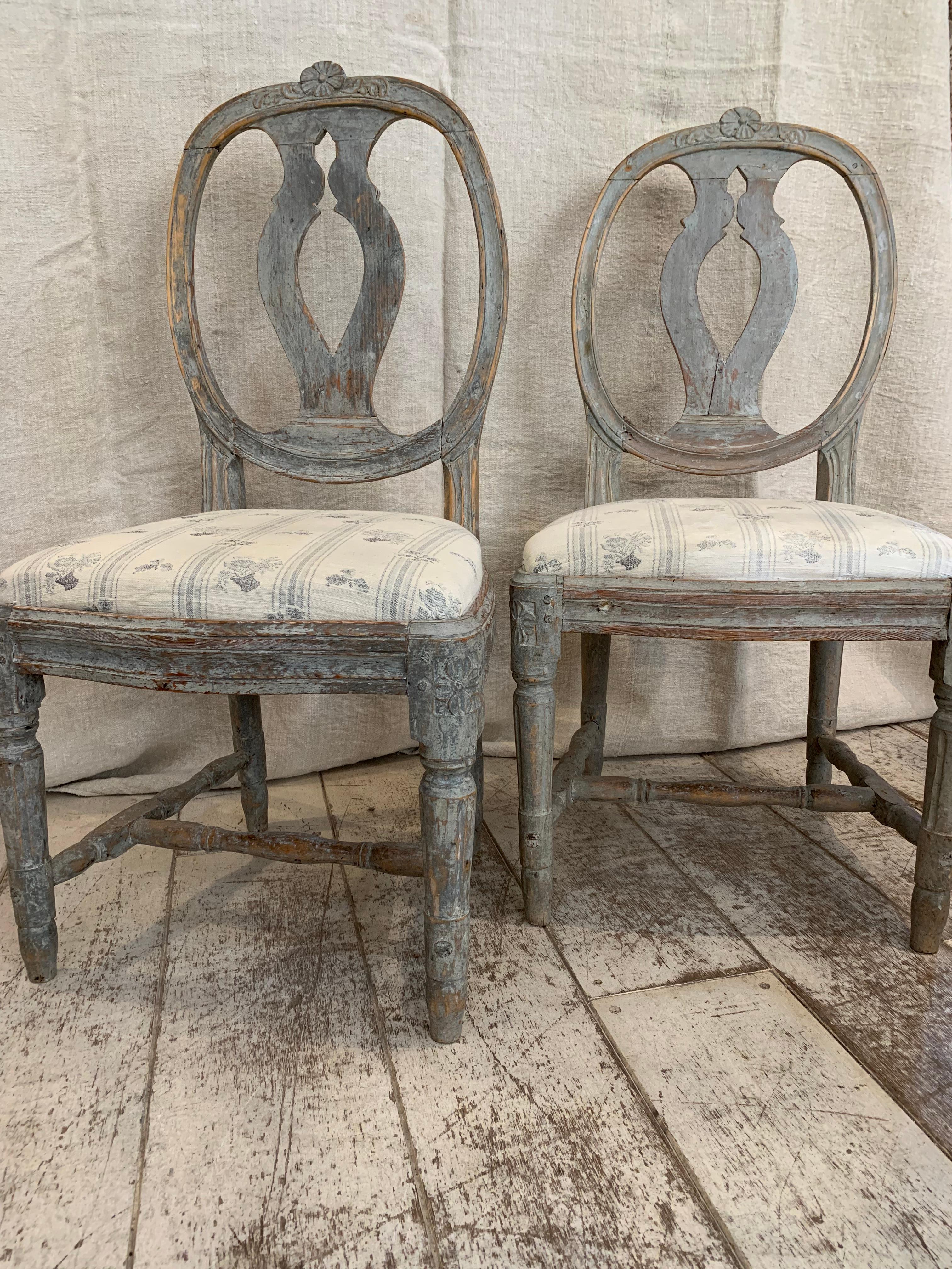 These late C18th chairs are a lovely example of Swedish Gustavian style.
The oval backrest has decorative cutouts and delicate carving to the top rim and the wood is painted in a typical historic blue-grey colour.
Their drop in seats have been