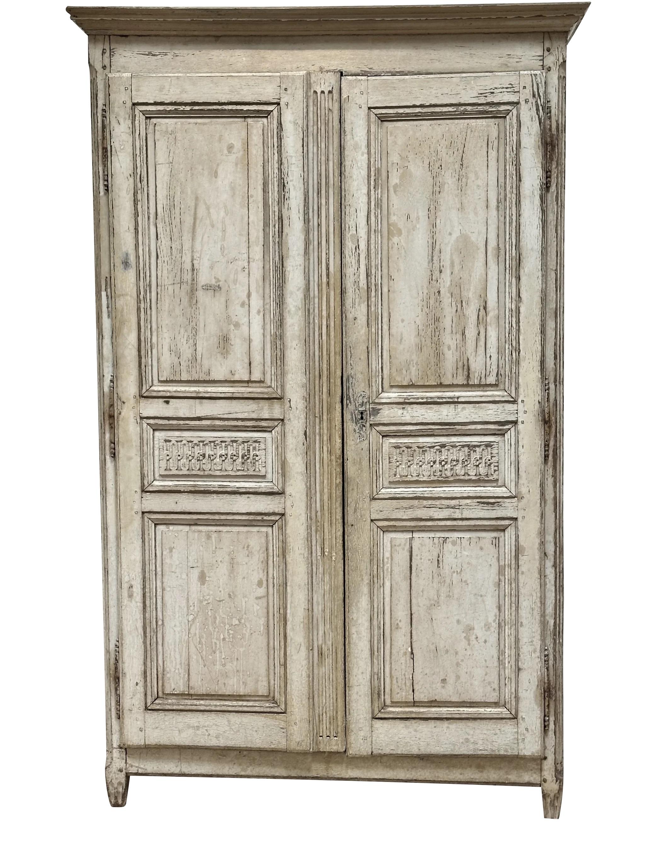18th Century Swedish armoire, having original pale grey/cream paint, the molded top over two carved doors, having charming guilloche detail to front doors, on slightly bulbous, reeded, tapered feet. Oak.  Currently fitted with 5 removable shelves.