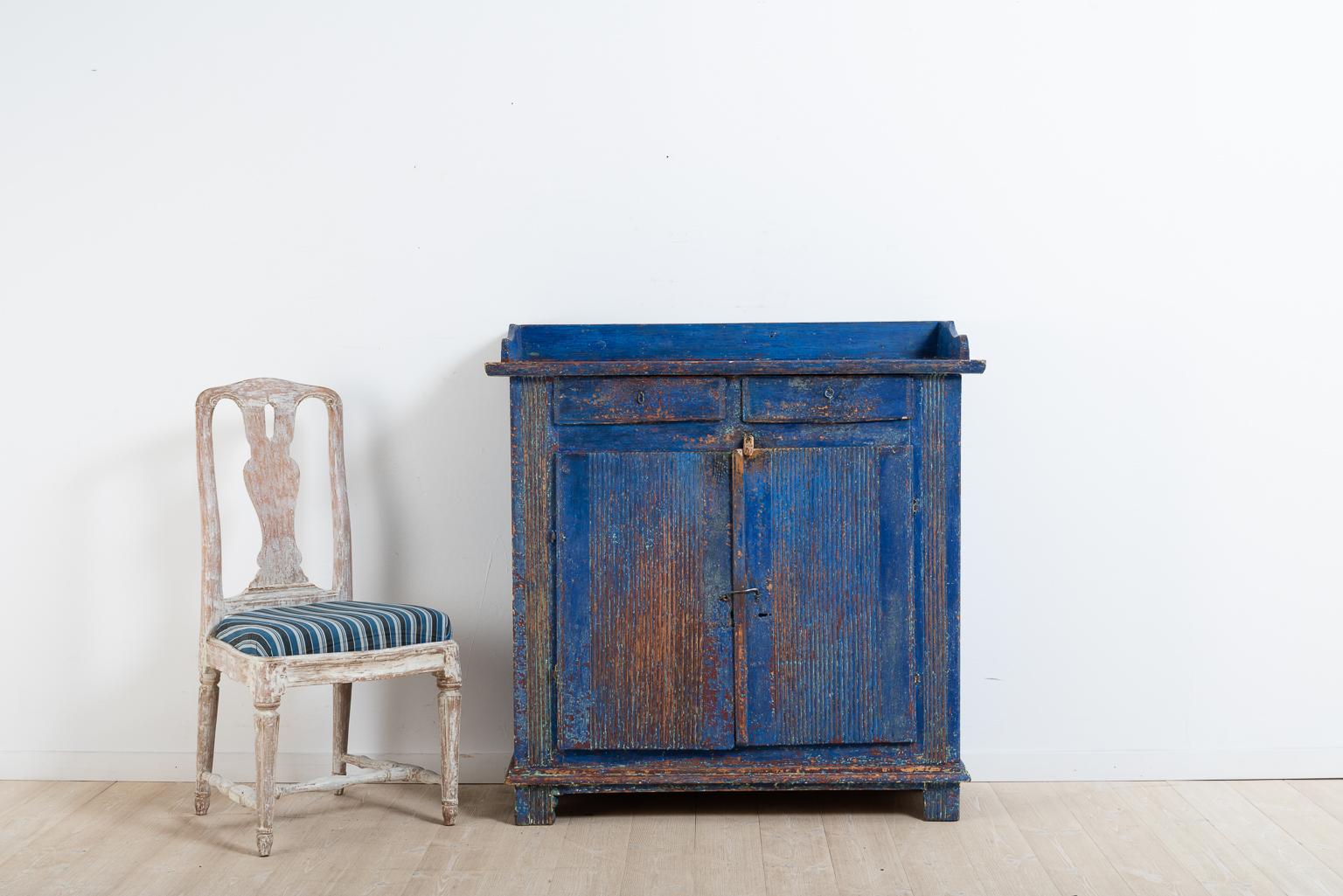 Provincial Gustavian sideboard with fluted decor. The sideboard has good patina all-over and old historic blue paint. The lock on the door is missing and has been replaced with a latch in wood and hook in handwrought iron. Both from the 19th