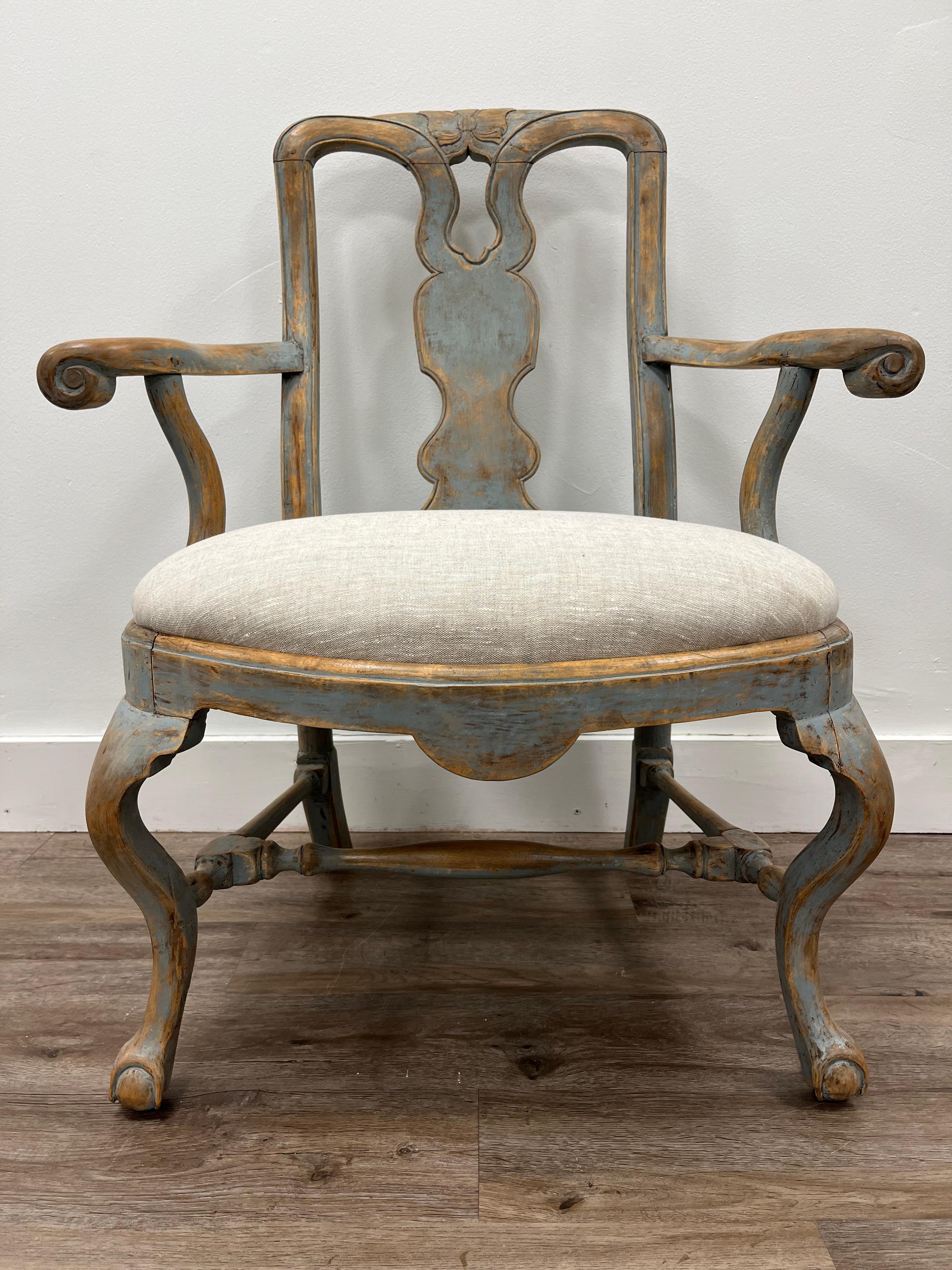 A fine Swedish Rococo armchair with carved backrest and turned arm rests. Wide seat atop cabriolet legs with turned H-cross construction. Tastefully repainted in pale blue and original seat has been reupholstered in linen. 