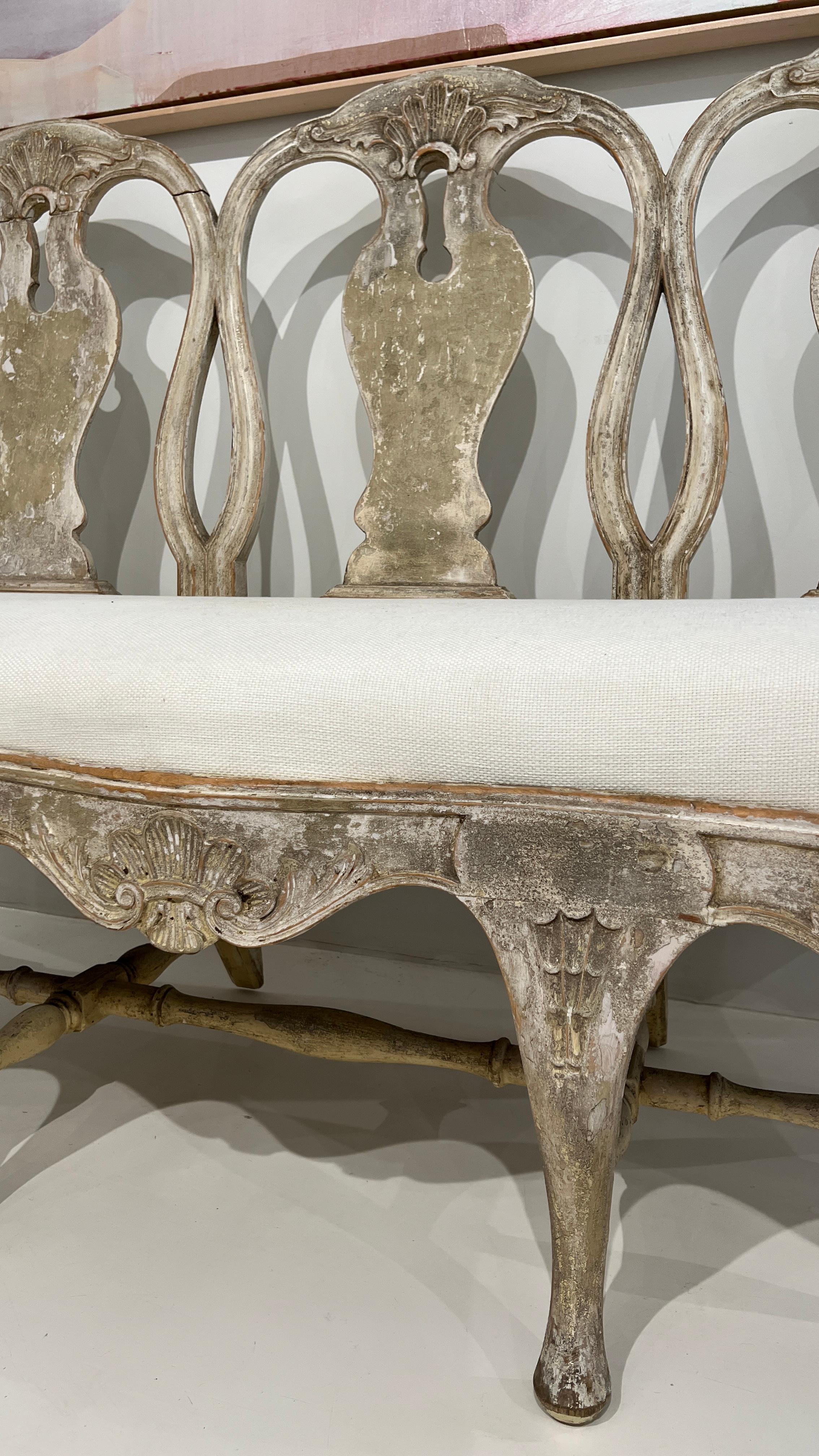 This rare and iconic 18th century Swedish Rococo Bench makes for quite the statement piece. Featuring light color of the painted wood along with the elegant keyholes. 