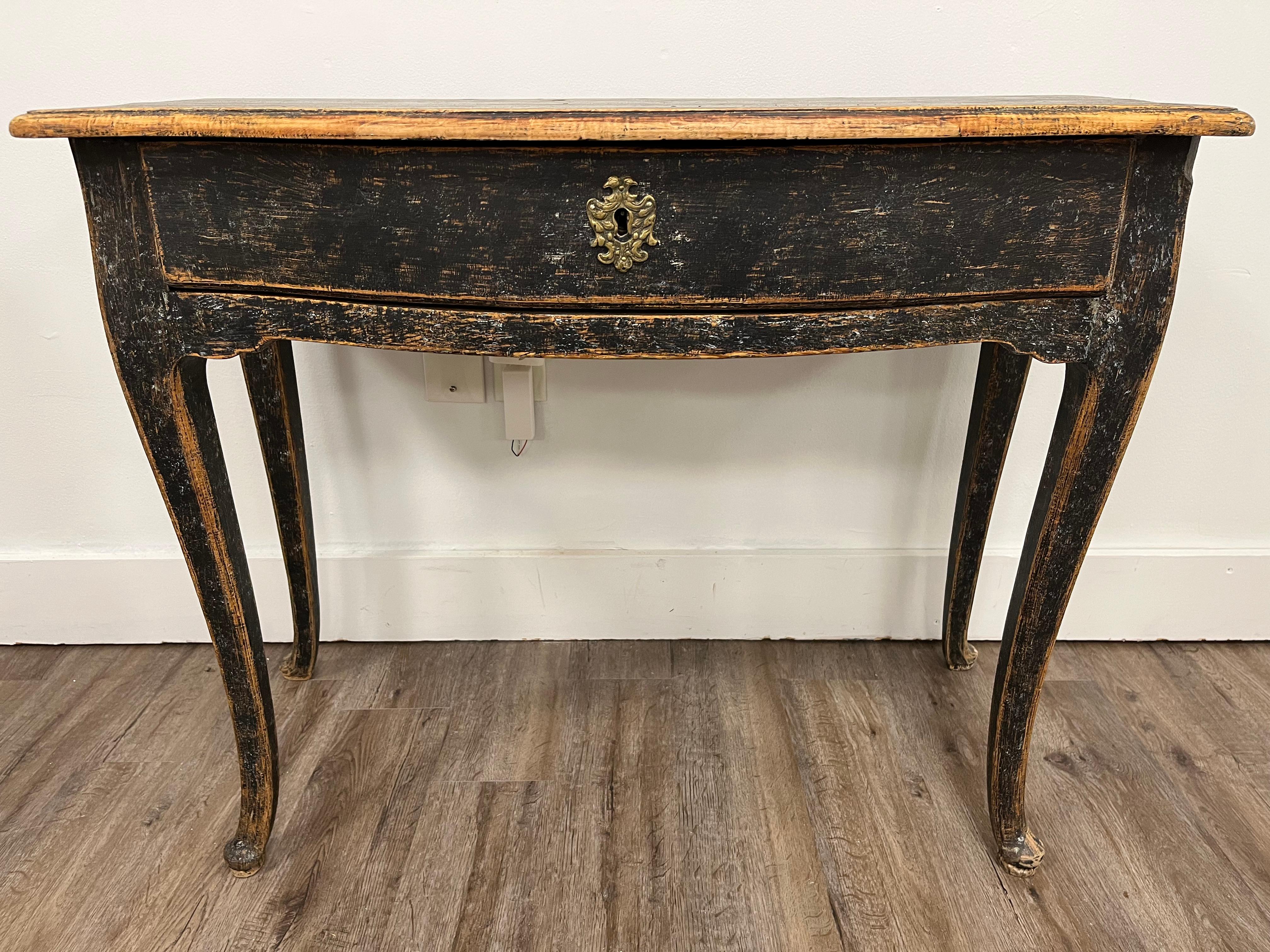 A Swedish Rococo console table with bow front shape and single drawer retaining its original brass hardware and iron lock. Tastefully repainted in black with traces of original blue paint inside the drawer. Sits atop cabriole legs.