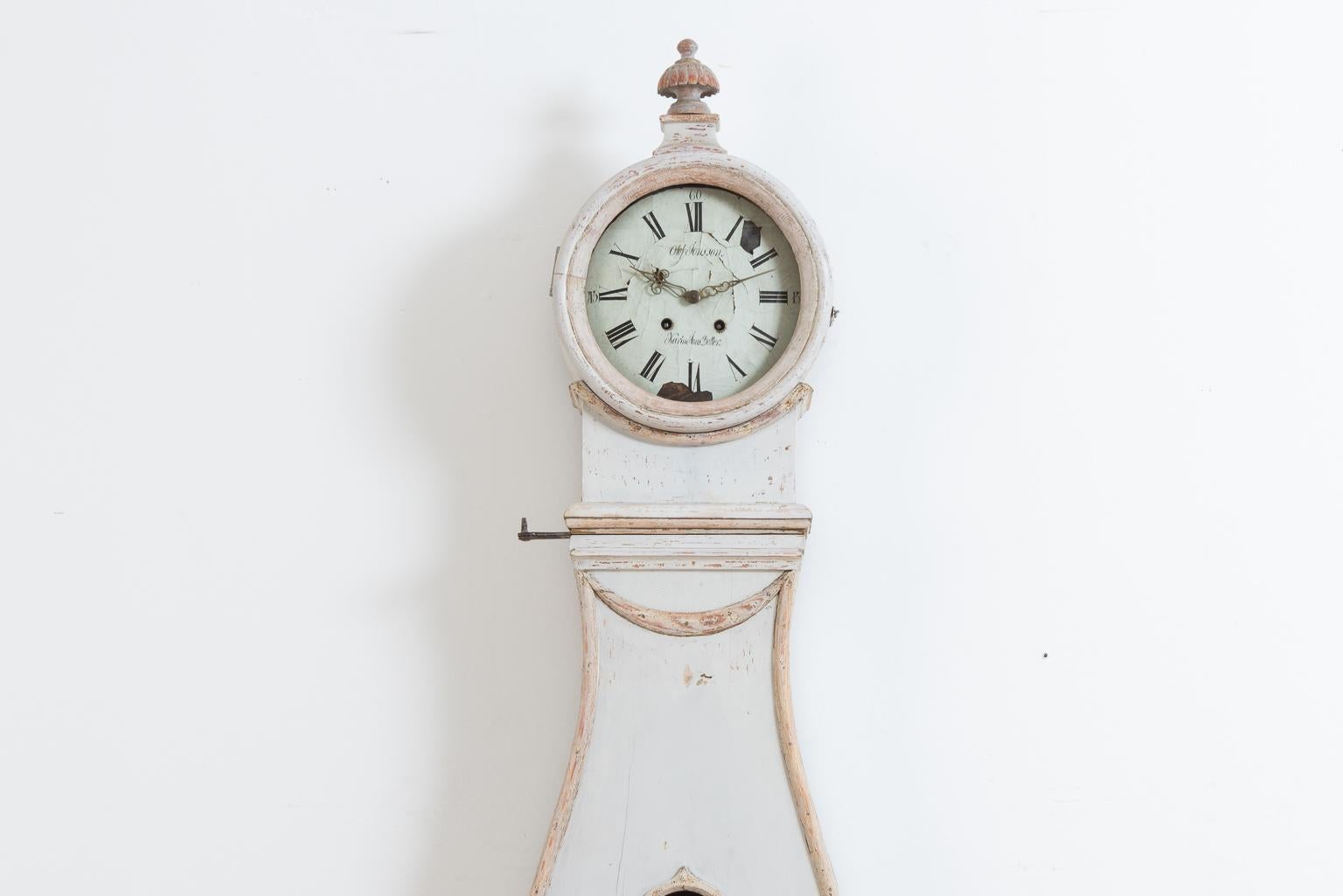 Rococo long case clock from Hälsingland. The paint is old and historic and from the 19th century. The clock has a solid and healthy frame manufactured from Swedish pine. The face has had some minor loss of material. The clock case have some signs of