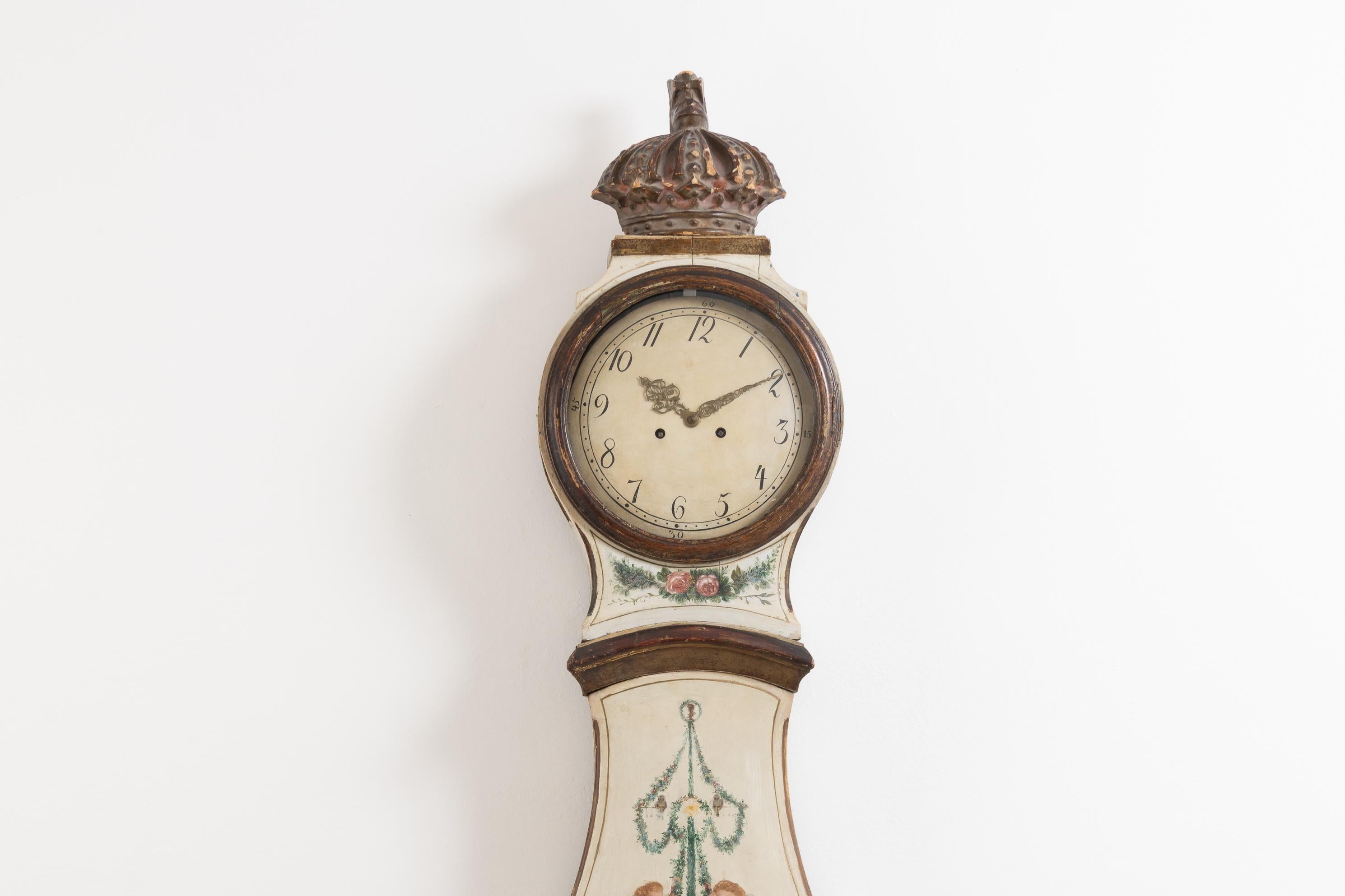 Long case Rococo clock with a curved case and large ornate headpiece. The clock was made in Stockholm, Sweden circa 1770. The headpiece is made from paper paper manchier in the shape of a crown. It is not fixed to the head and can be taken off. The