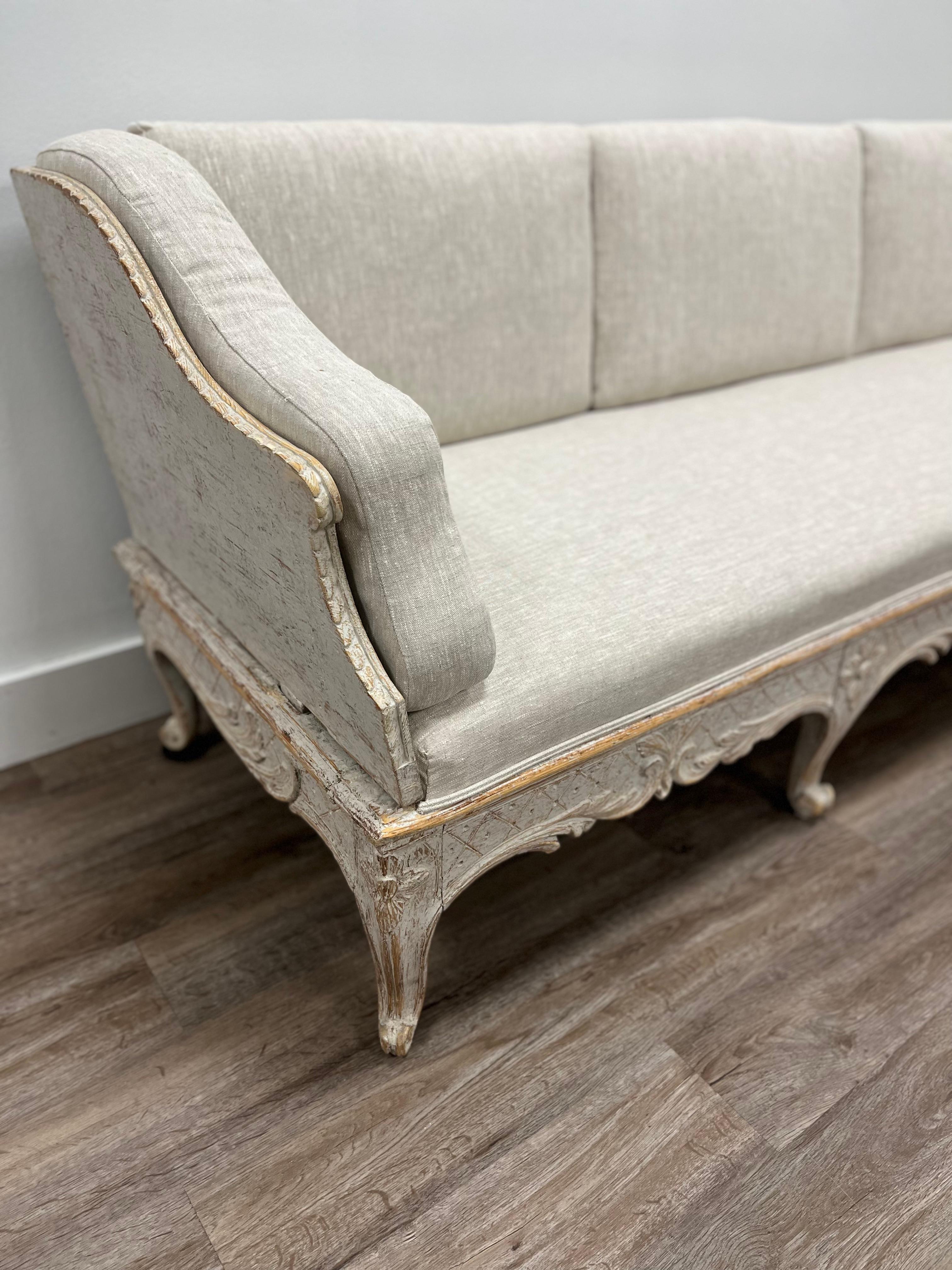 An exquisite Swedish tragsofa with traditional Rococo shape and design (e.g. cabriole legs, curves and counter-curves) and Gustavian carvings (e.g. cross hatching, floral detail above the legs). A unique transitional piece made in Stockholm.