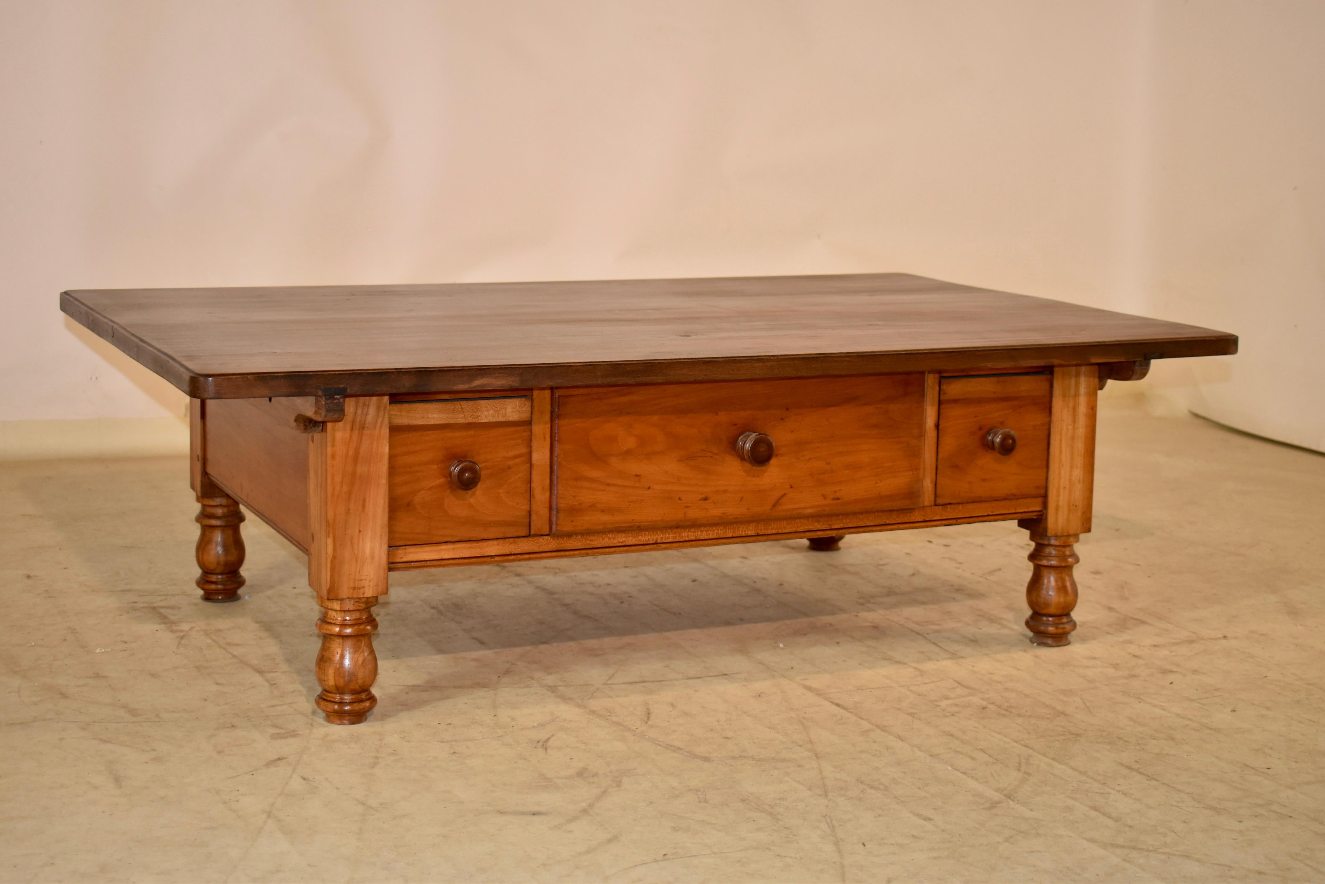 18th century Swiss coffee table made from cherry. The top is made from wide boards with wonderful graining and a beveled edge with chamfered corners. The apron is simple and has three drawers in the front. The table is supported on hand turned legs.