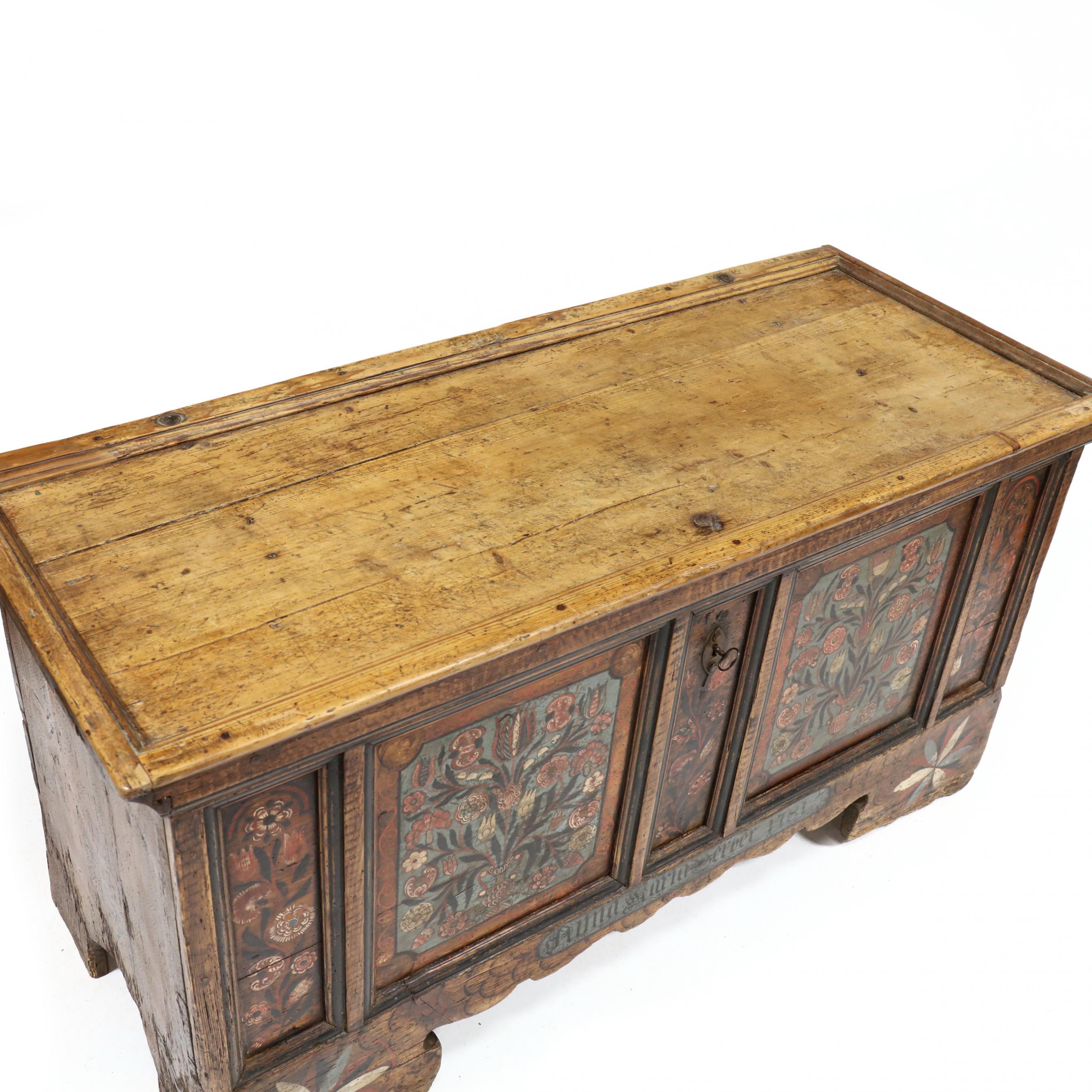 18th Century Swiss Dowry Chest. Made of pine and mixed woods, hinged lid with paneled top and through tenon joinery, iron strap hinges, original iron clasp and lock with key. The front case panels with nicely painted flowering urns over a