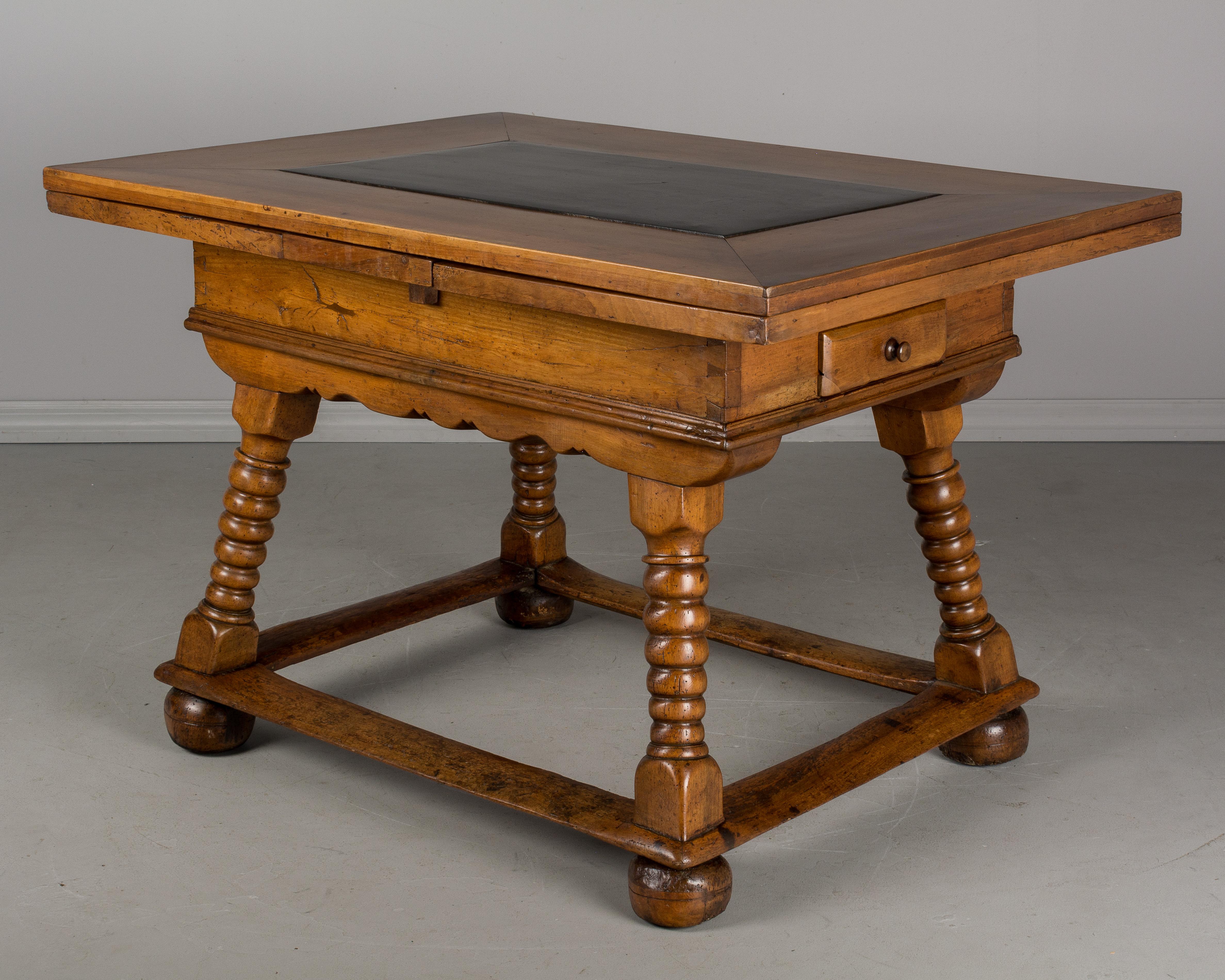 An 18th century Swiss farm table, or extension dining table made of solid walnut with a black slate inset. Sturdy base with turned legs and square stretcher. Two 18