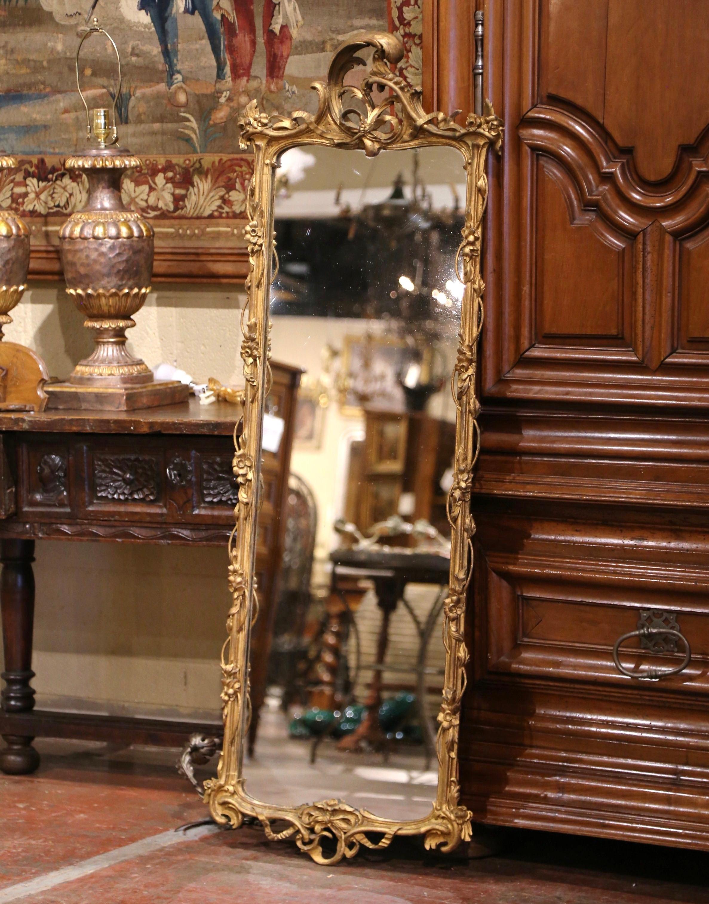 This ornate and elegant carved wall mirror was crafted in Italy, circa 1780. Five feet tall, the antique mirror features an ornate, gilded frame with intricate Rococo-style carvings. The frame is adorned with scrolling acanthus leaves, floral