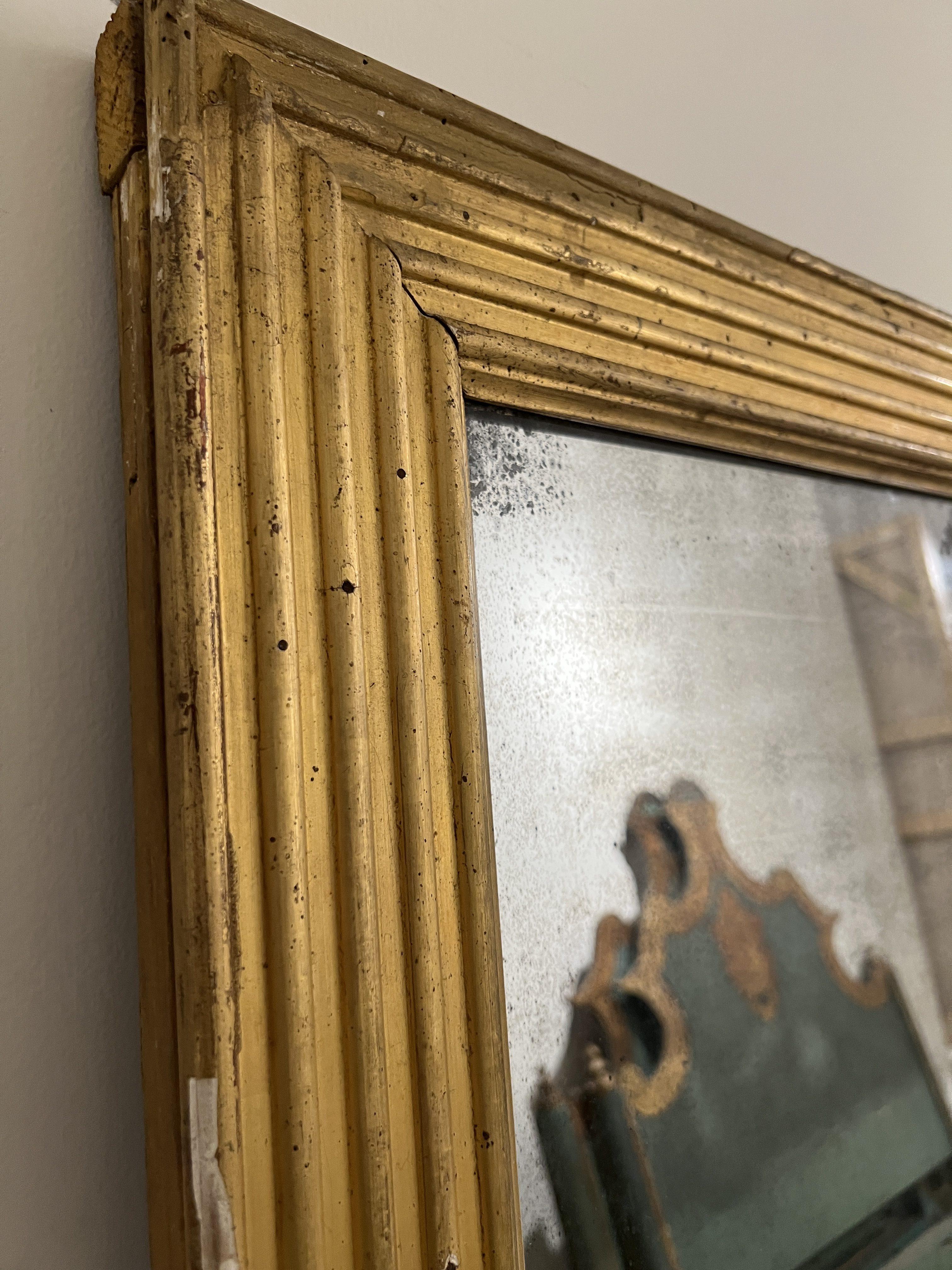 Rare et raffiné miroir de style Louis XVI français du XVIIIe siècle. Il est doté d'une double vitre d'origine insérée dans un cadre en bois doré finement sculpté et orné de bordures cannelées néoclassiques illustrant l'élégance et la symétrie de