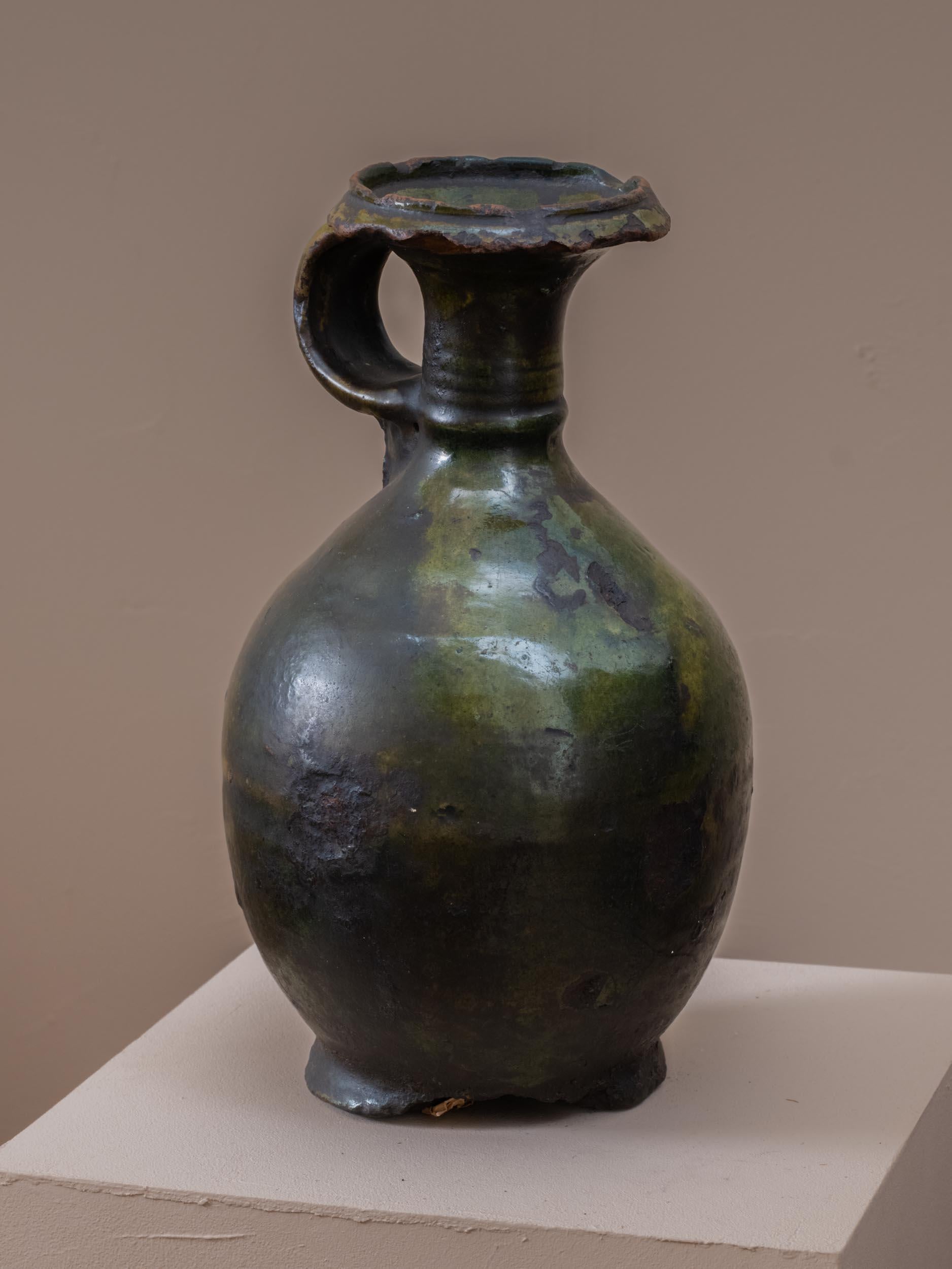 Il s'agit d'une pièce rare de poterie ancienne de Tamegrout. Sa glaçure naturelle caractéristique, composée de minéraux, de cuivre et de poudre d'orge, a développé au fil des ans une patine unique et envoûtante.
Ces cruches de taille moyenne