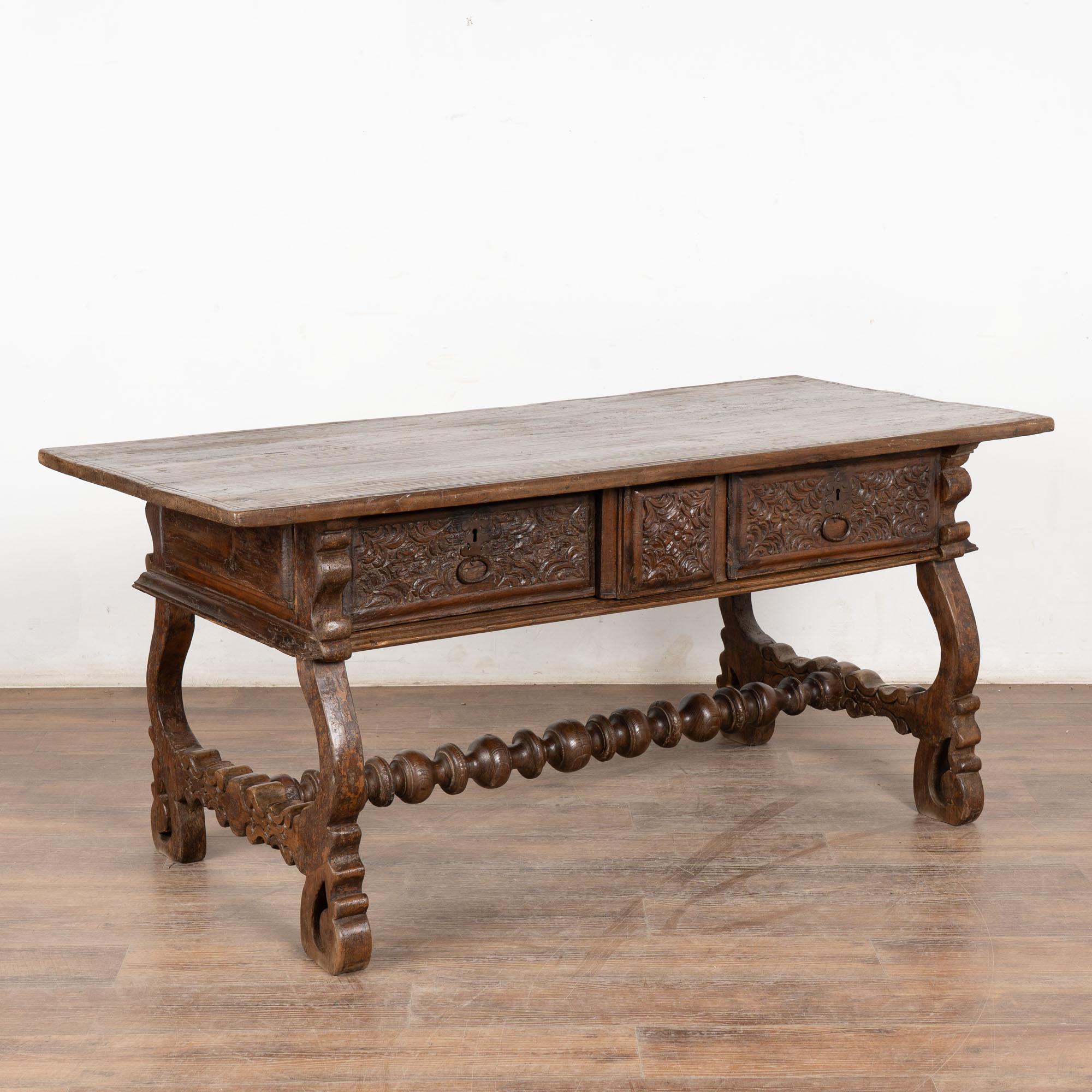 Console en noyer foncé à trois tiroirs reposant sur des pieds en forme de harpe et un châssis tourné décoratif.
Les trois tiroirs sont ornés de détails sculptés à la main. Les deux tiroirs extérieurs sont dotés d'une tirette. Le petit tiroir central