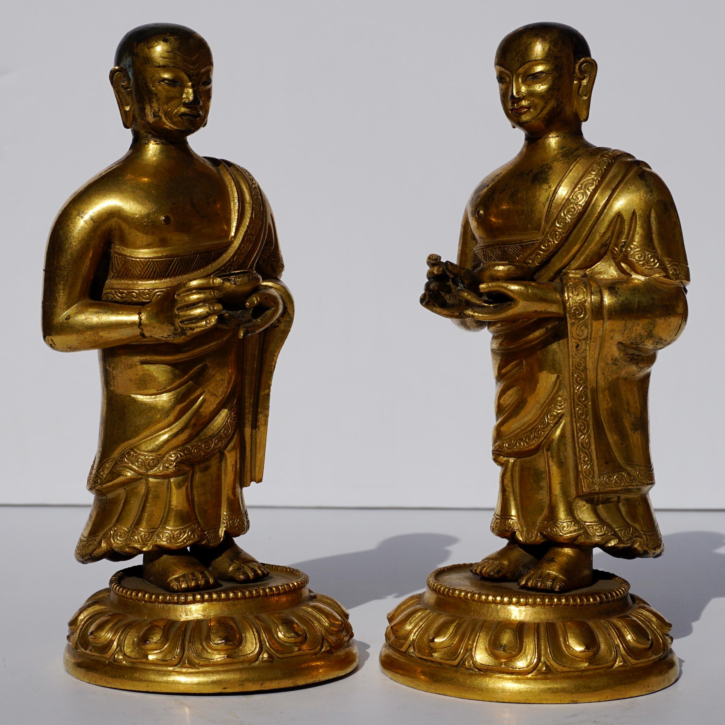 A rare pair of Sino-Tibetan gilt bronze and repousse Lama or Lohan standing figures. They are ceremoniously robed holding bowls in their left hands, They have different distinctive faces and the detailed repousse is outstanding. A real rarity to