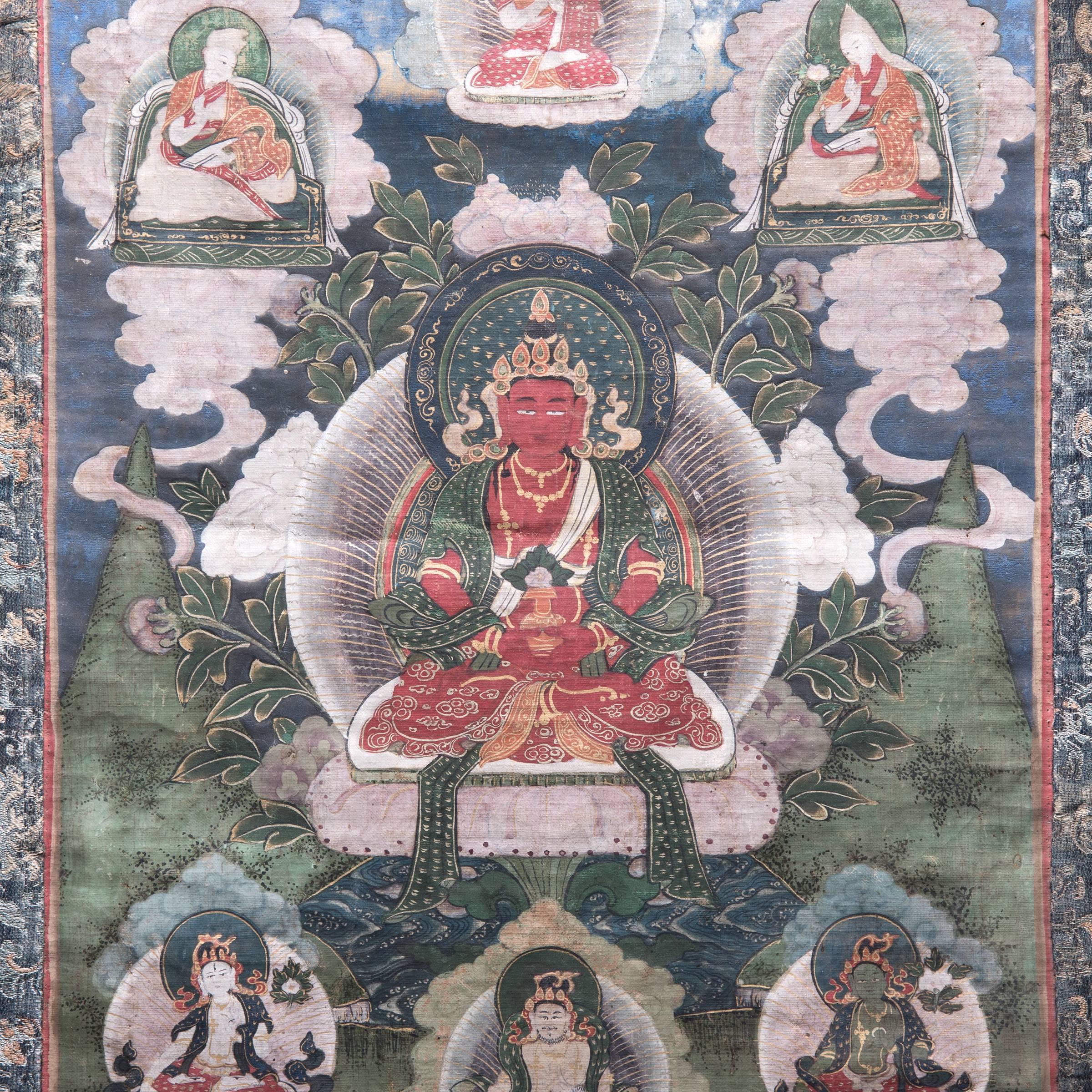 The followers of the cult of Amitayus, the Buddha of Eternal Life, believed that their devotion to this Buddha would prolong their lives. In this beautifully detailed Tibetan Thangka, the central figure of Amitayus is rendered in a brilliant shade
