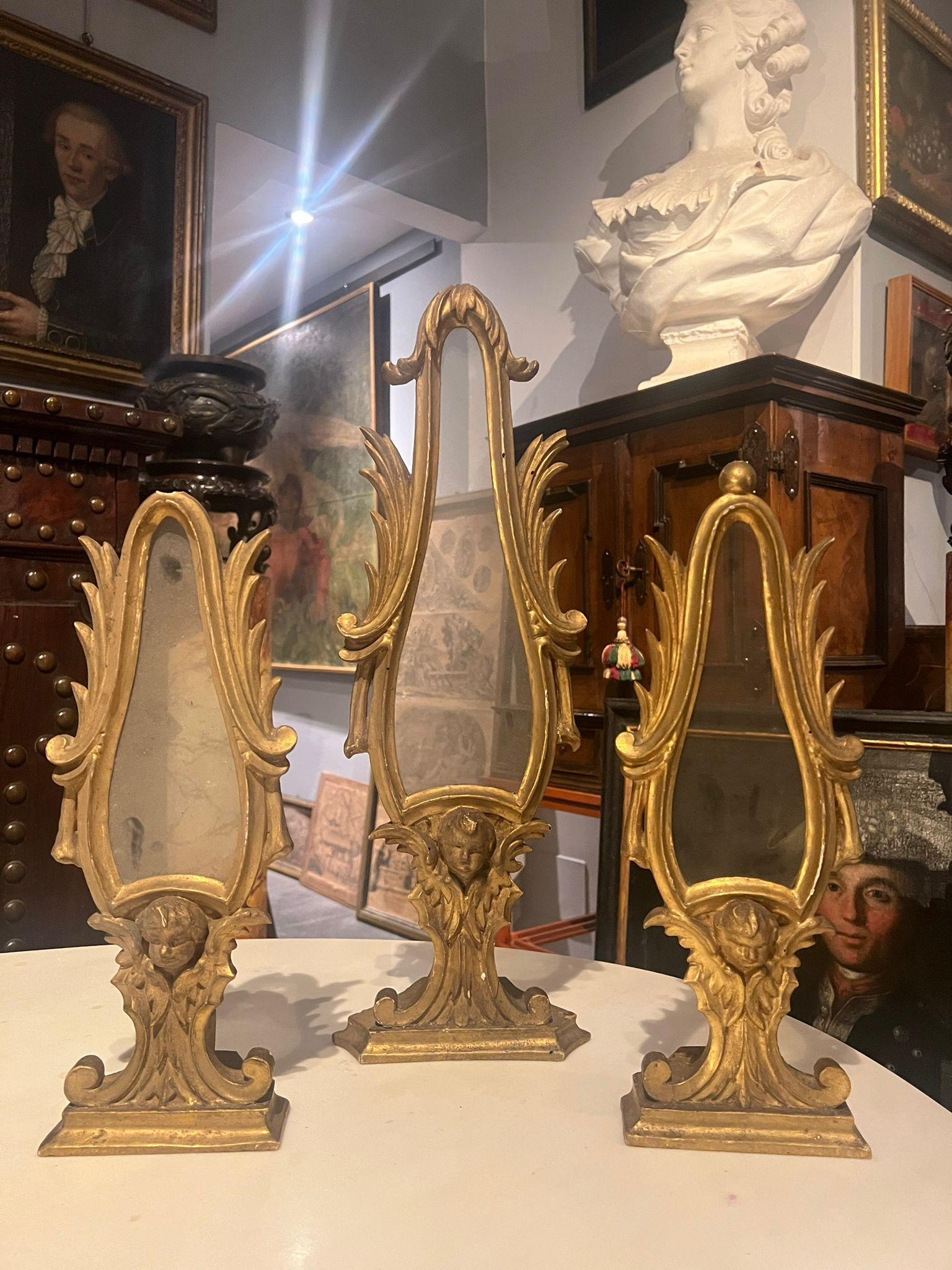 Beautiful triptych of relic holders in carved and gilded wood. Very particular in their shape, in the lower part they have a finely carved angel's head with wings, Tuscany, 18th century.

The relics are absent.

To be restored.

Dimensions: