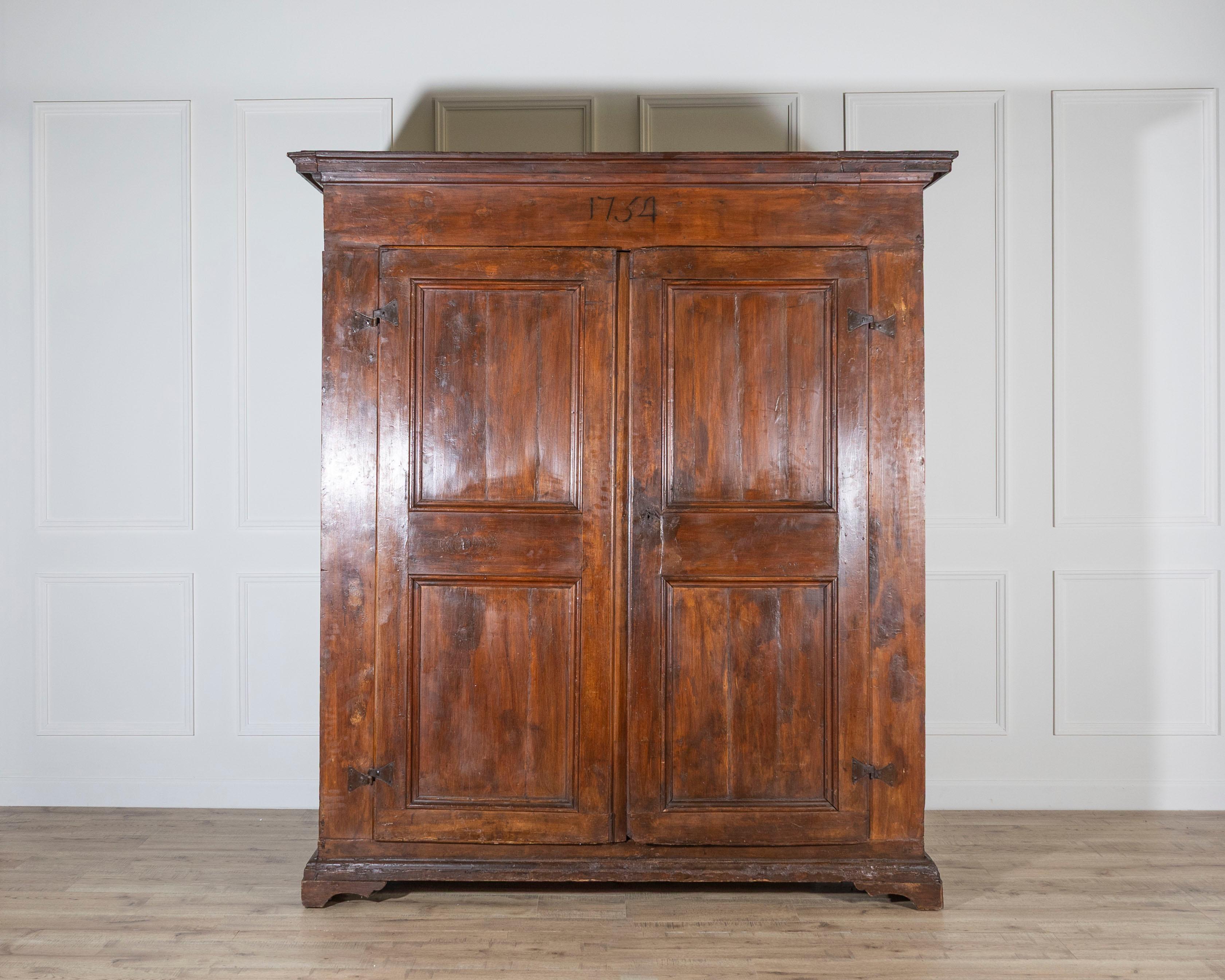 A stately 18th-century Italian wardrobe, handcrafted in solid poplar and dated 1751, as inscribed across the upper frieze. Originating from Tuscany, this elegant armoire reflects the region’s restrained yet noble craftsmanship of the period. The two