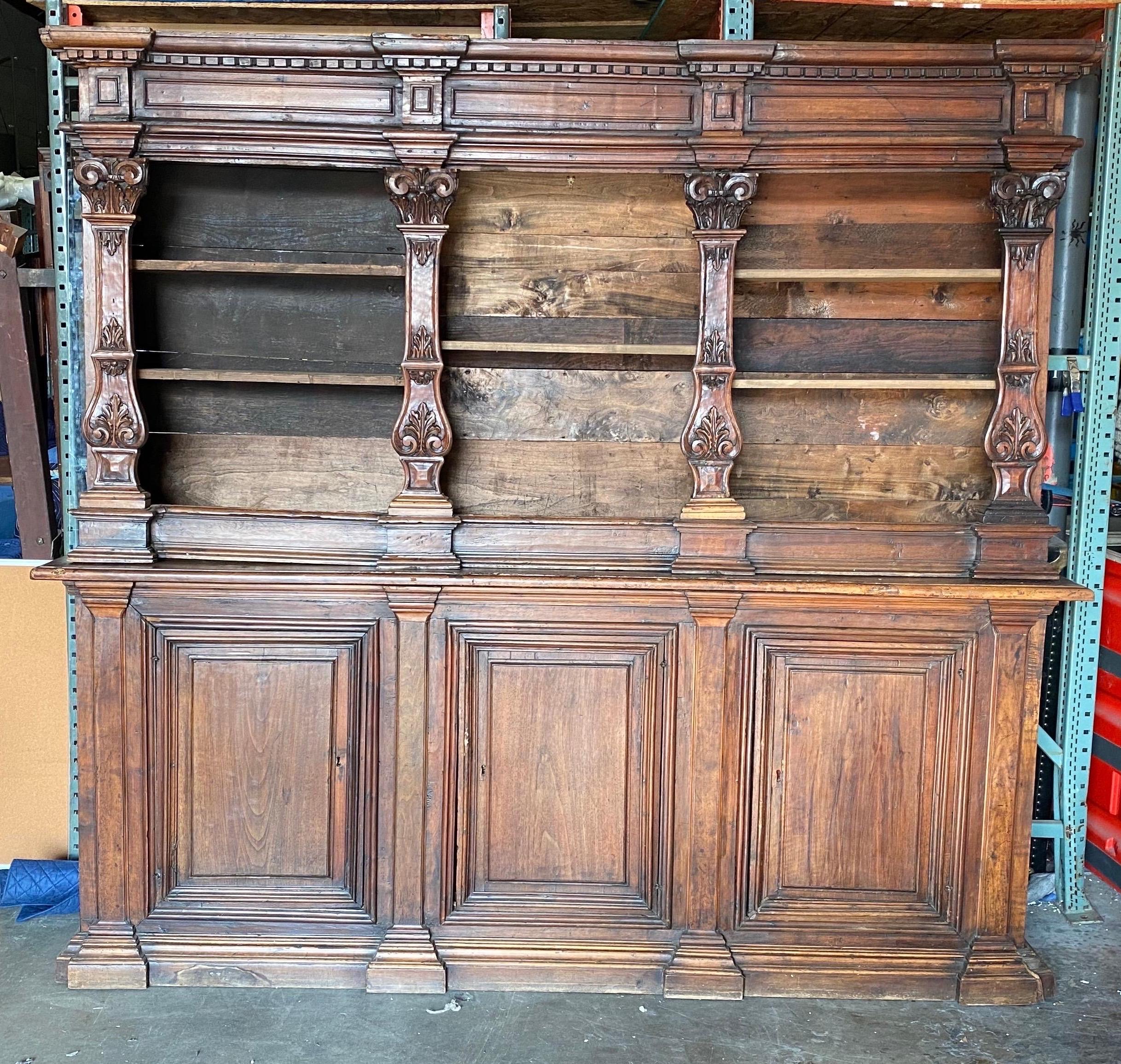 18th century Tuscan walnut bookcase. Two parts- top is has adjustable shelves and the base has three doors revealing more shelves. Hand carved throughout.