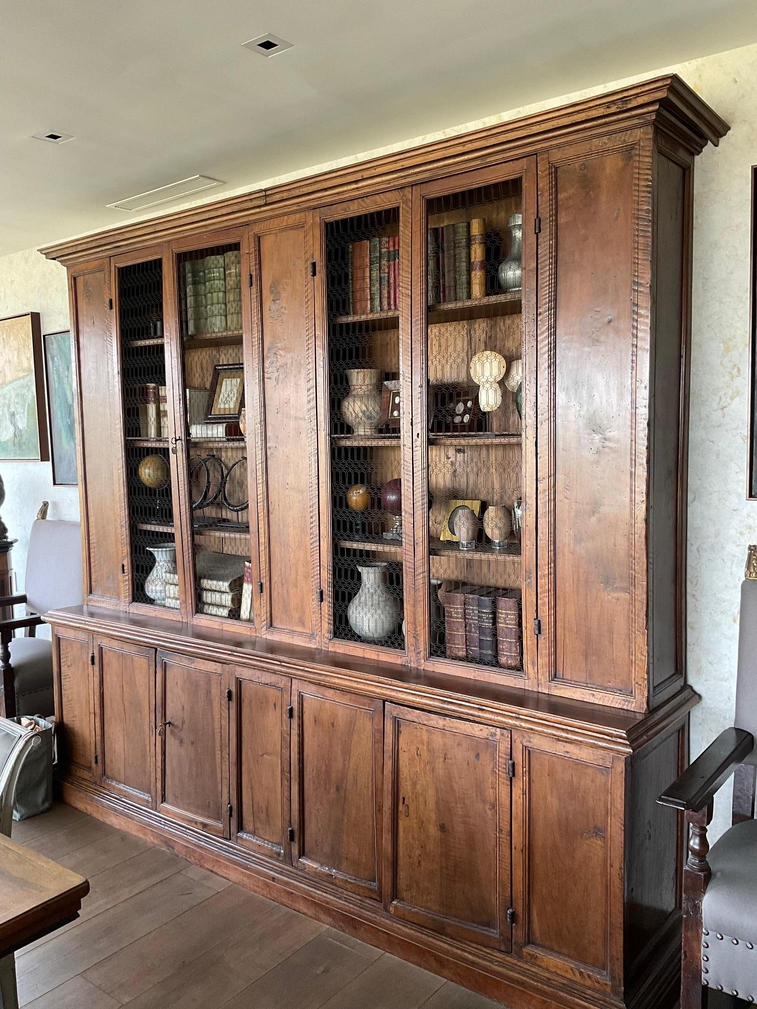 18th-century Tuscan walnut bookcase with original wire mesh cabinet doors. The base features concealed doors for increased storage. Handsome and capacious, this special piece has great dimensions and a rich, warm patina. 

Italy, circa
