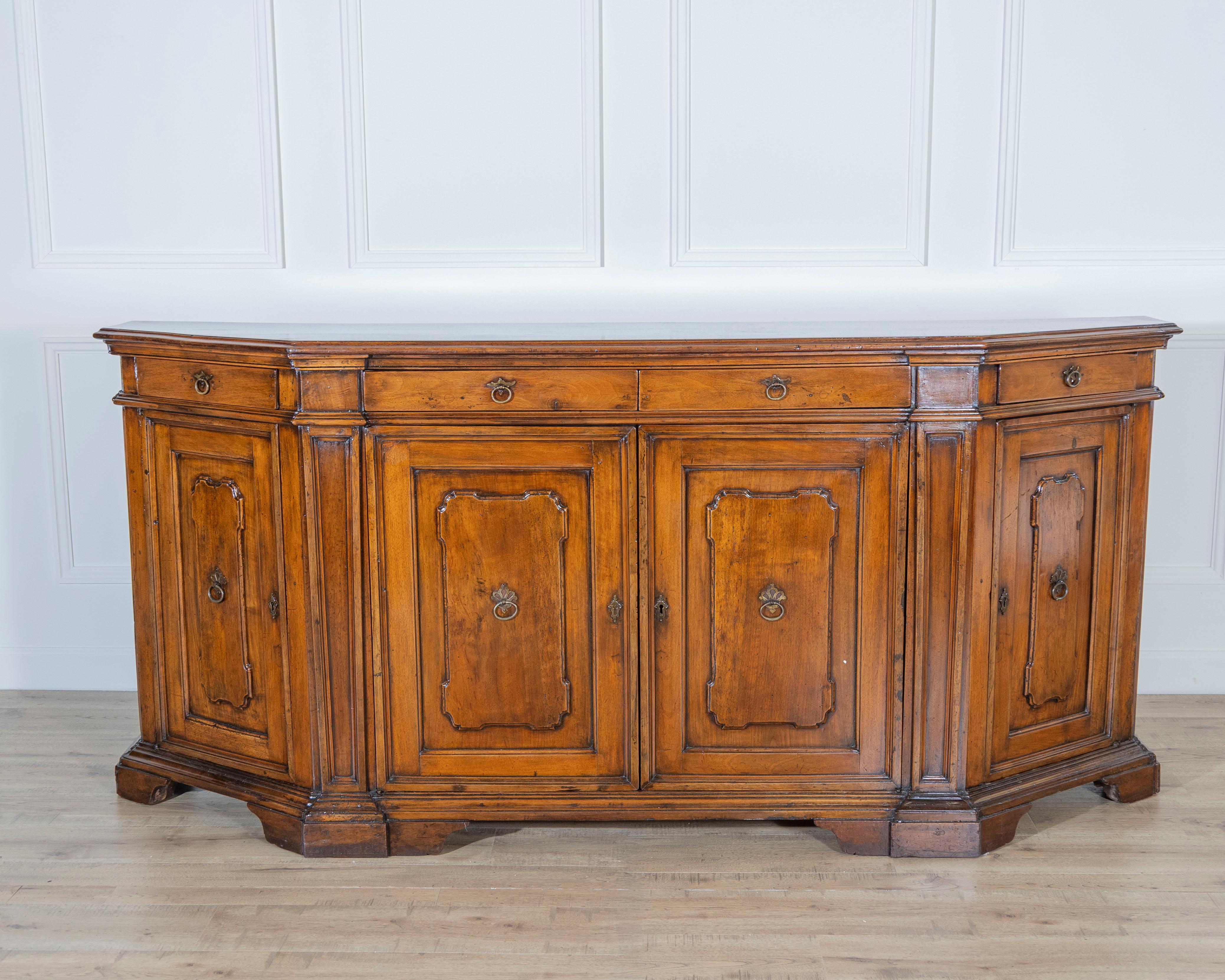 An exceptional 18th-century Tuscan sideboard, masterfully crafted in solid walnut and distinguished by its cornered, architectural form. This rare piece embodies the understated grandeur of aristocratic Tuscan interiors, where elegance met utility