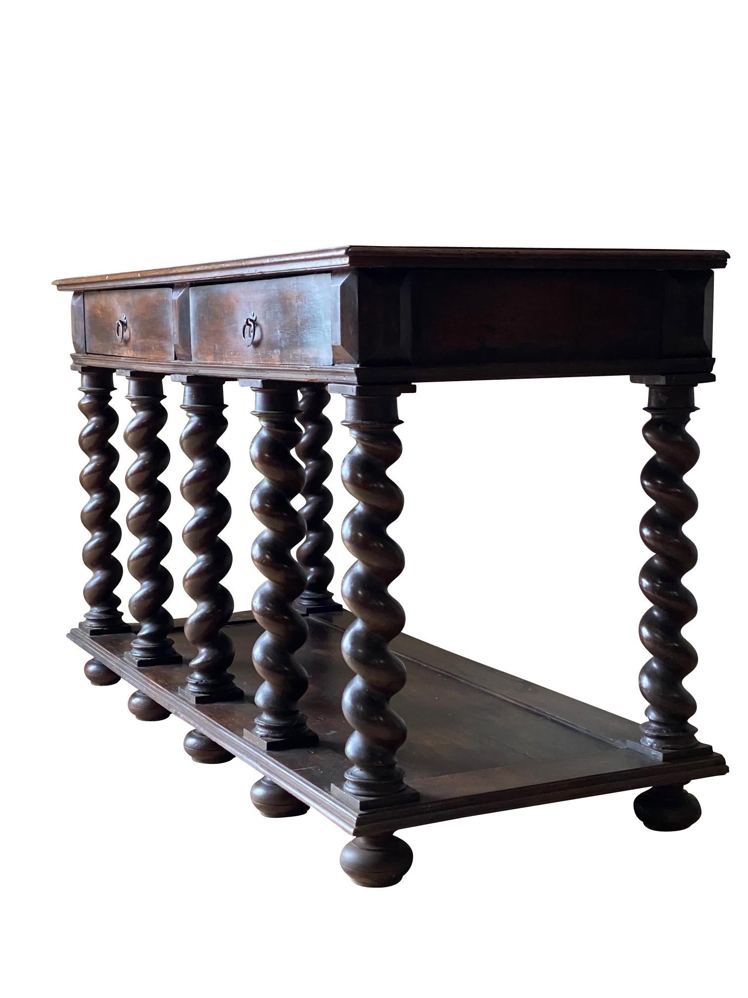 18th century Italian two-drawer walnut console.
The console has seven turned legs and a lower tier shelf.
Recently refinished.
 