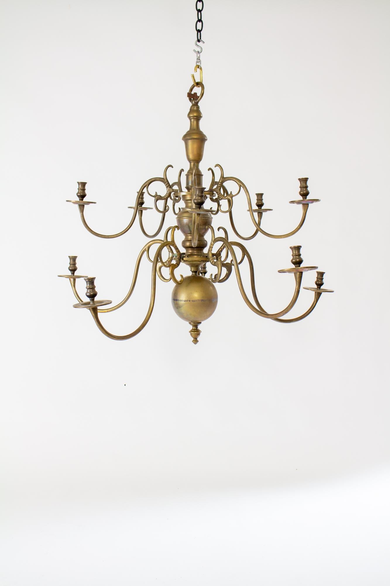18th Century two tier Dutch colonial brass chandelier with ten arms. Turned Central brass stem with an urn shaped top and bottom ball. Two tiers of five arms extend from the center. The arms hook with square pegs onto plates in the stem. Solid