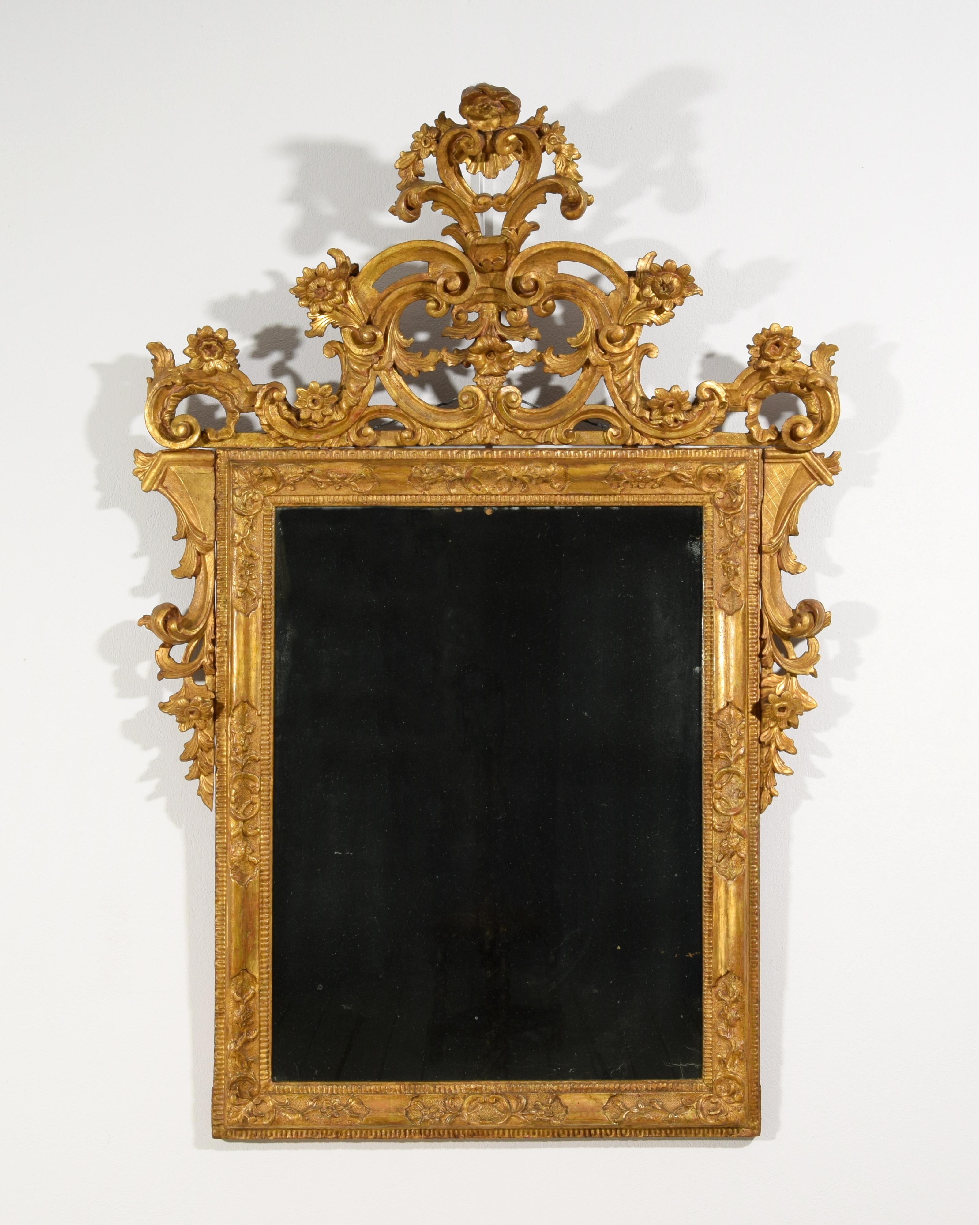 18th century, Venetian Baroque Giltwood mirror 

The refined mirror was made in the Venetian area, Italy, in the 18th century in finely carved and gilded wood.
It has a rectangular frame with floral carvings in relief inside two geometric