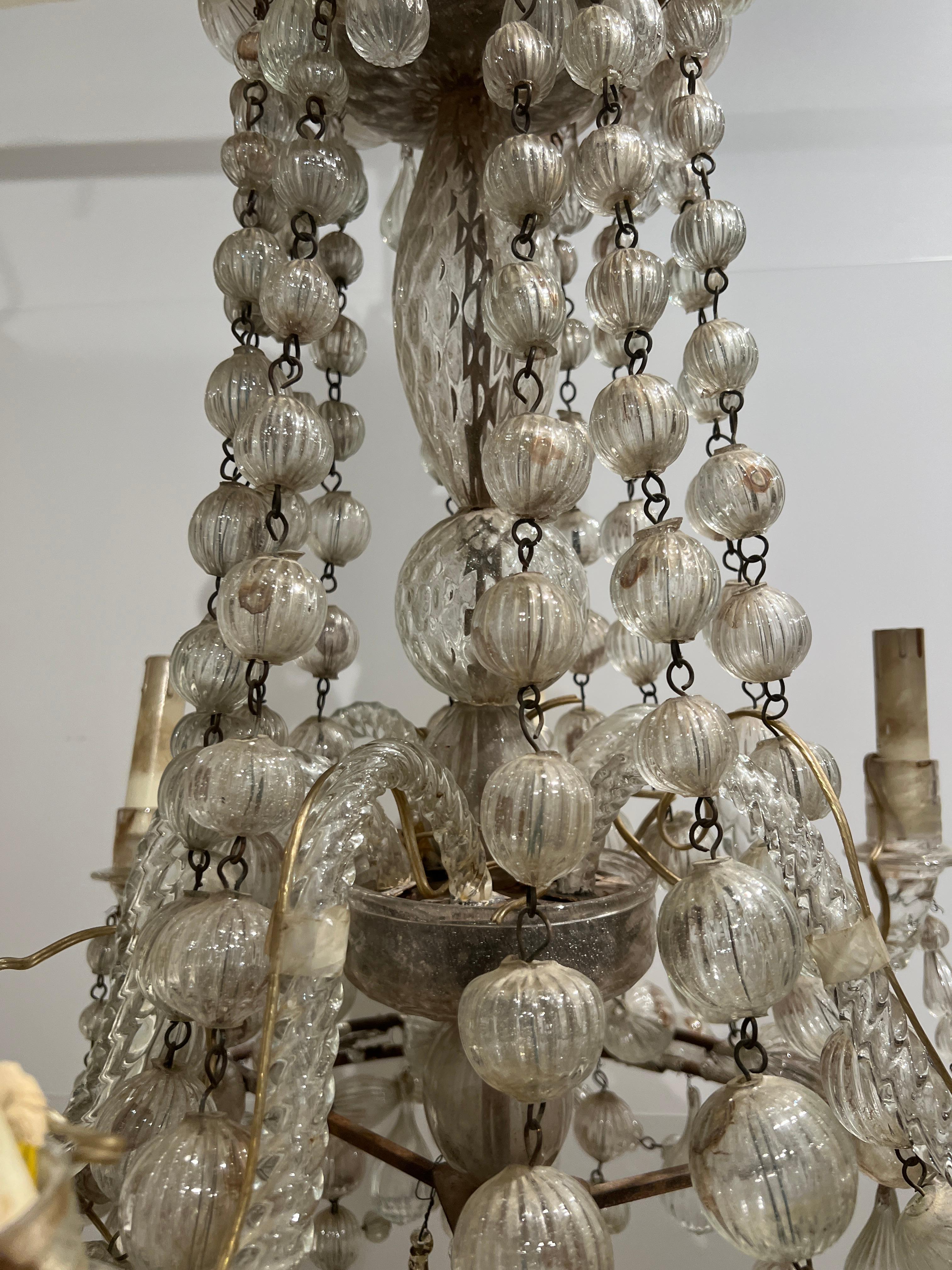 18th century Venetian chandelier with hand blown glass. Exquisite leafed crown at the top and bottom. Ribbed glass balls decorate the bands at top and bottom of the chandelier with accents of ribbed drops as well. 8 glass arms. Fine craftsmanship.