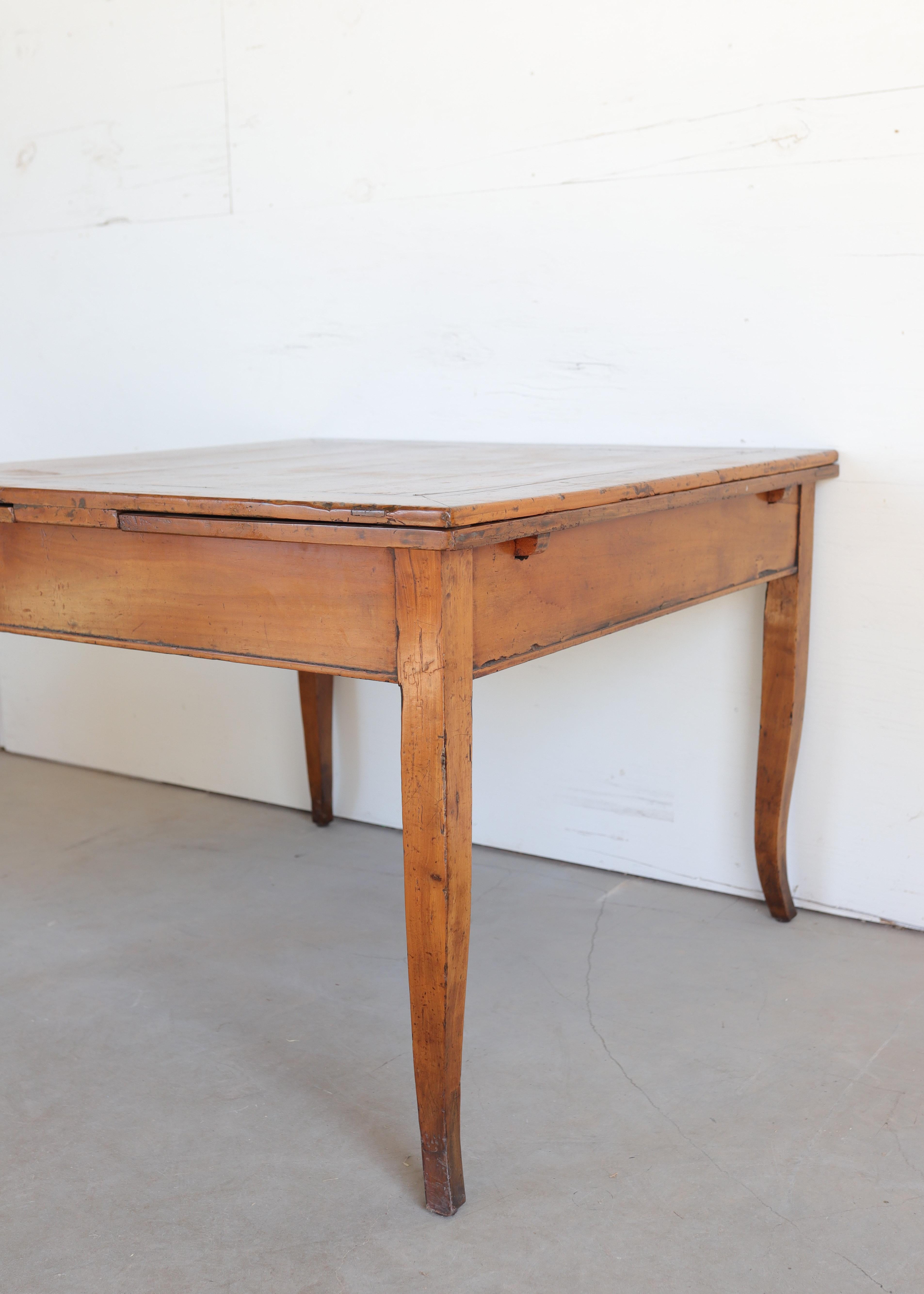 Une élégante table vénitienne du XVIIIe siècle fabriquée en cerisier aux tons chauds et mielleux, aux proportions raffinées et aux gracieux pieds cabriole. La forme carrée s'ouvre pour révéler deux feuilles extensibles astucieusement dissimulées,