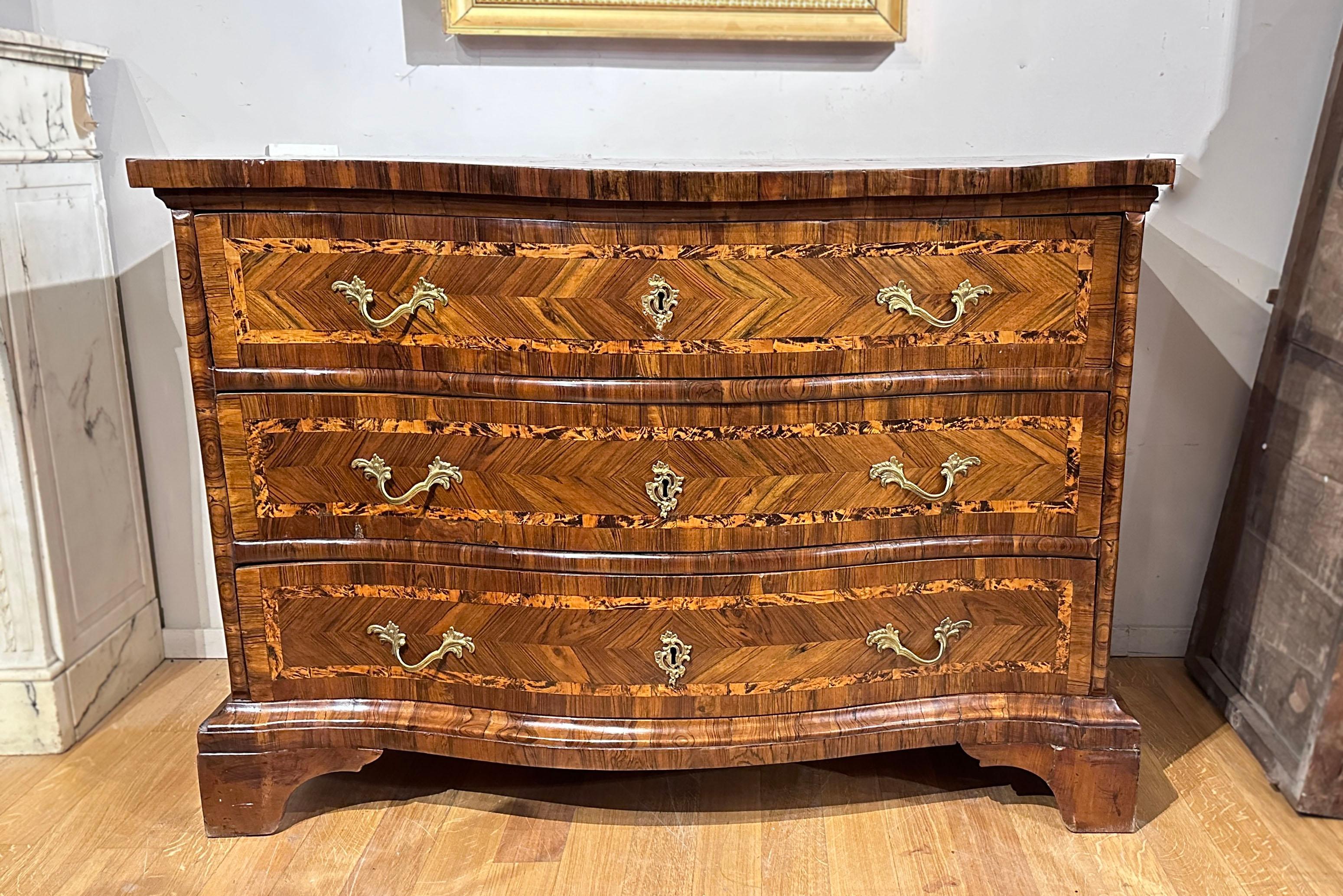 Beautiful and refined Venetian chest of drawers, characterized by a wavy front veneered in walnut briar and maple briar. It has a linear shelf base which gives the furniture great stability. This chest of drawers is also extremely practical and