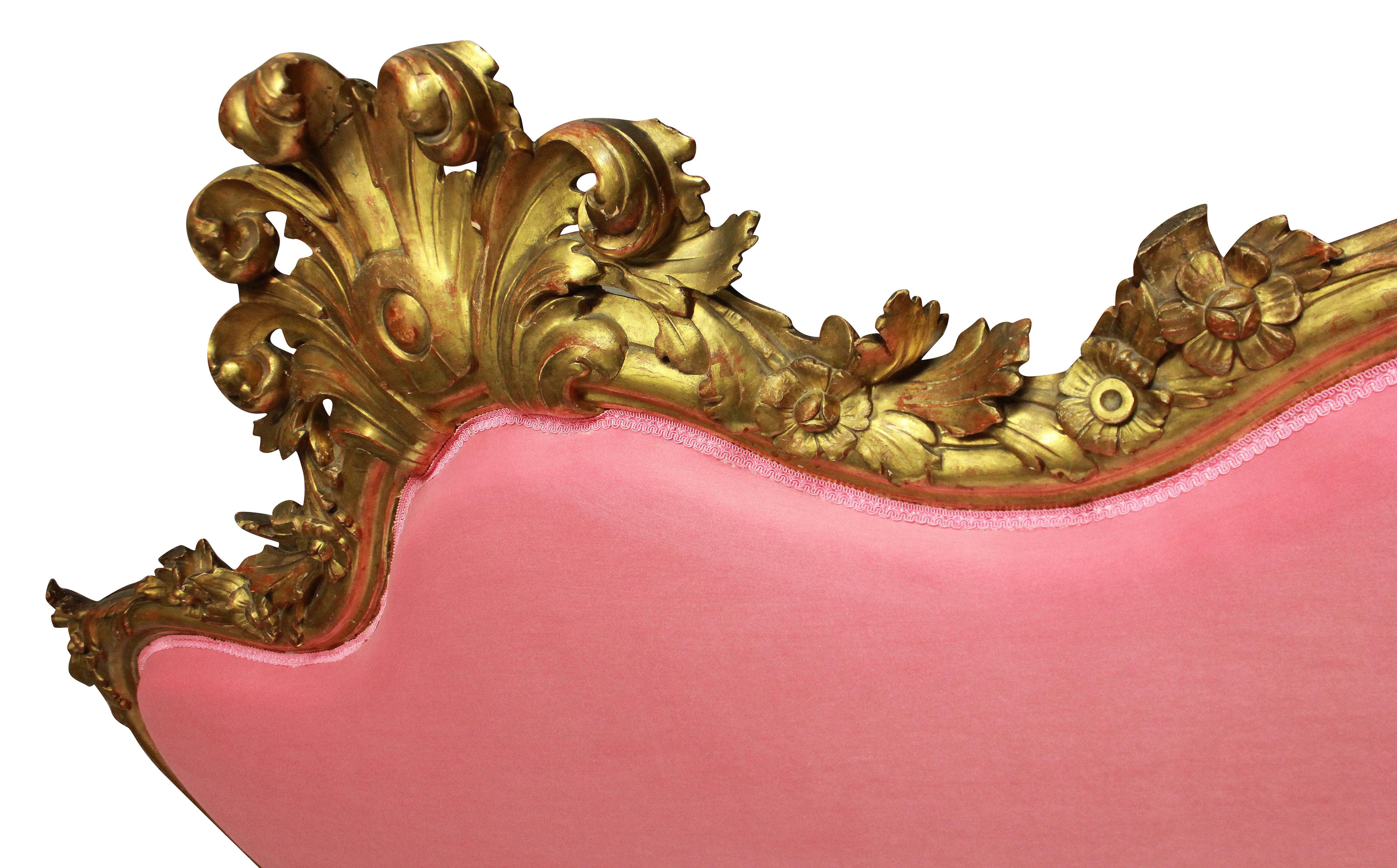 A fine 18th century Venetian carved giltwood settee, with shell crest and lion mask and paw feet, amongst boldly carved and water gilded foliage. Newly upholstered in bubblegum pink velvet.