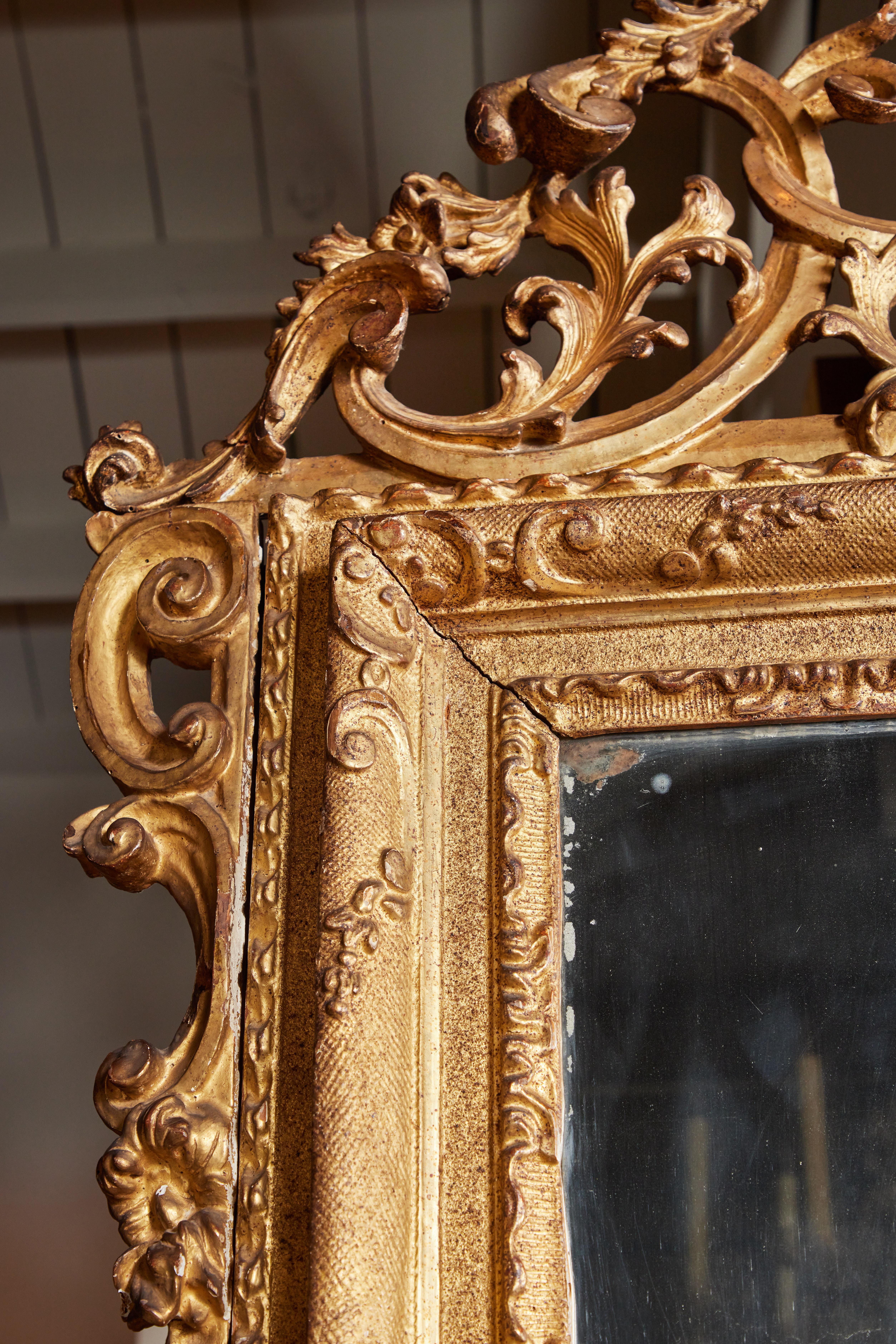 Großer, handgeschnitzter, gessoierter und 22-karätig vergoldeter venezianischer Spiegel, um 1760, mit originalem Quecksilberglas eingesetzt und von serpentinenartigen Reliefschnitzereien umgeben. Das Ganze wird von einer prachtvollen,