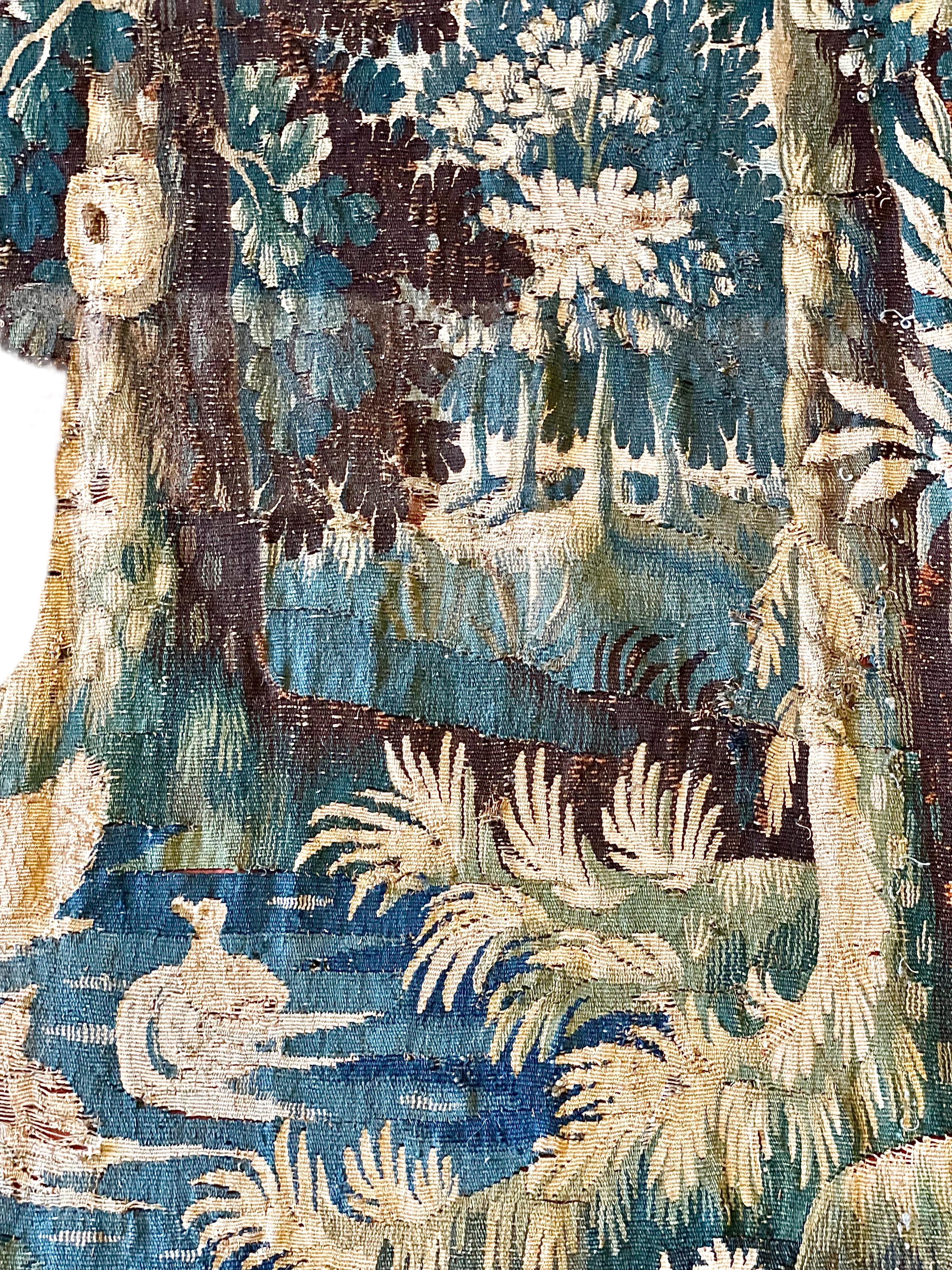 A luxurious 18th-century Aubusson tapestry, depicting a dog barking at fowl on a river, in a typically rural and architectural-themed landscape. Hand-woven in wool, in predominantly green and cream hues with a border on all sides, this antique wall