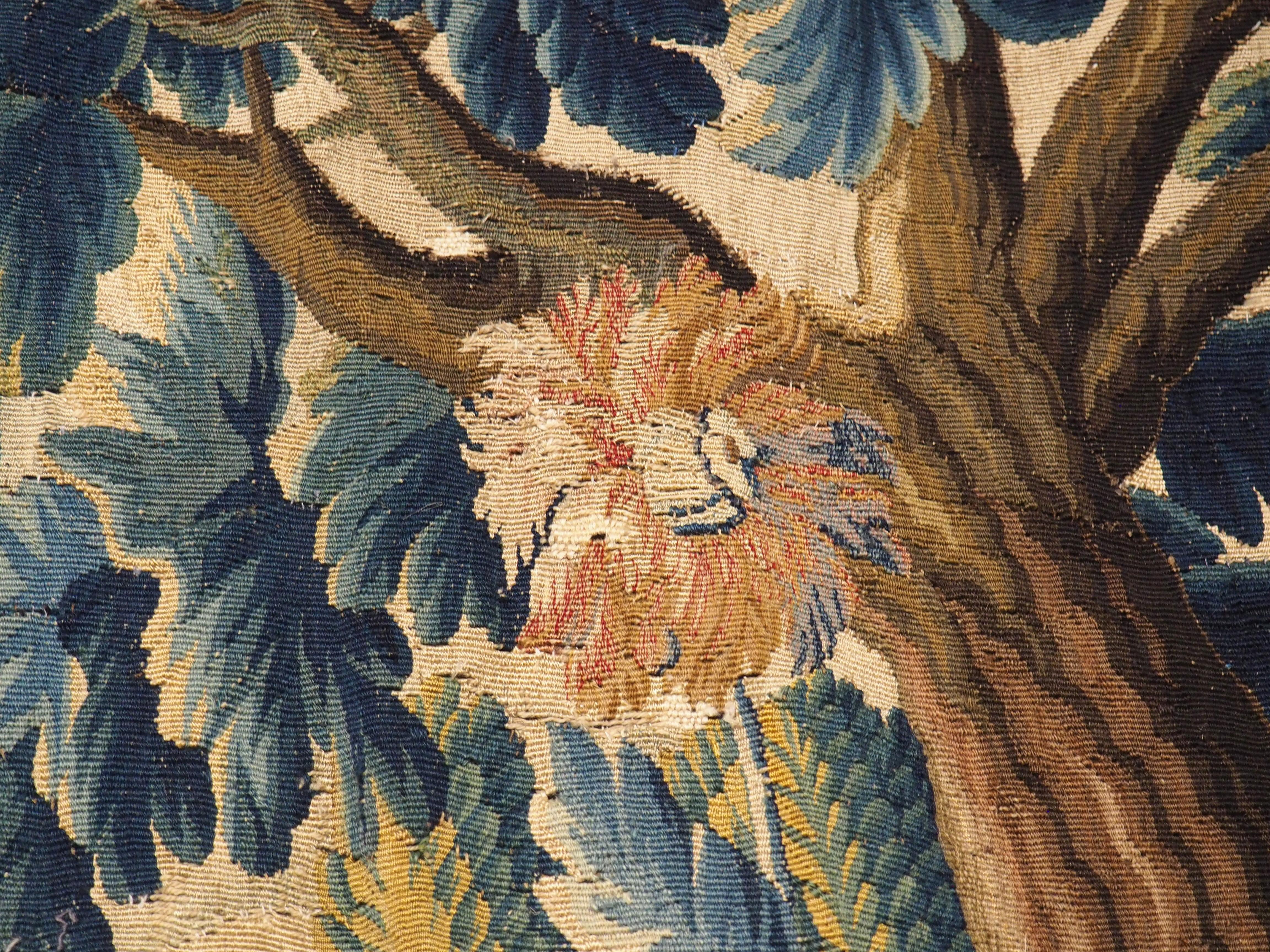 Dieser Wandteppich aus Wolle und Seide wurde um 1700 in Flandern (Teil des heutigen Belgiens) von Hand gewebt und zeigt ein dichtes Blätterdach außerhalb einer ummauerten Stadt. Dieser Webstil, der für die Darstellung üppiger, grüner Vegetation