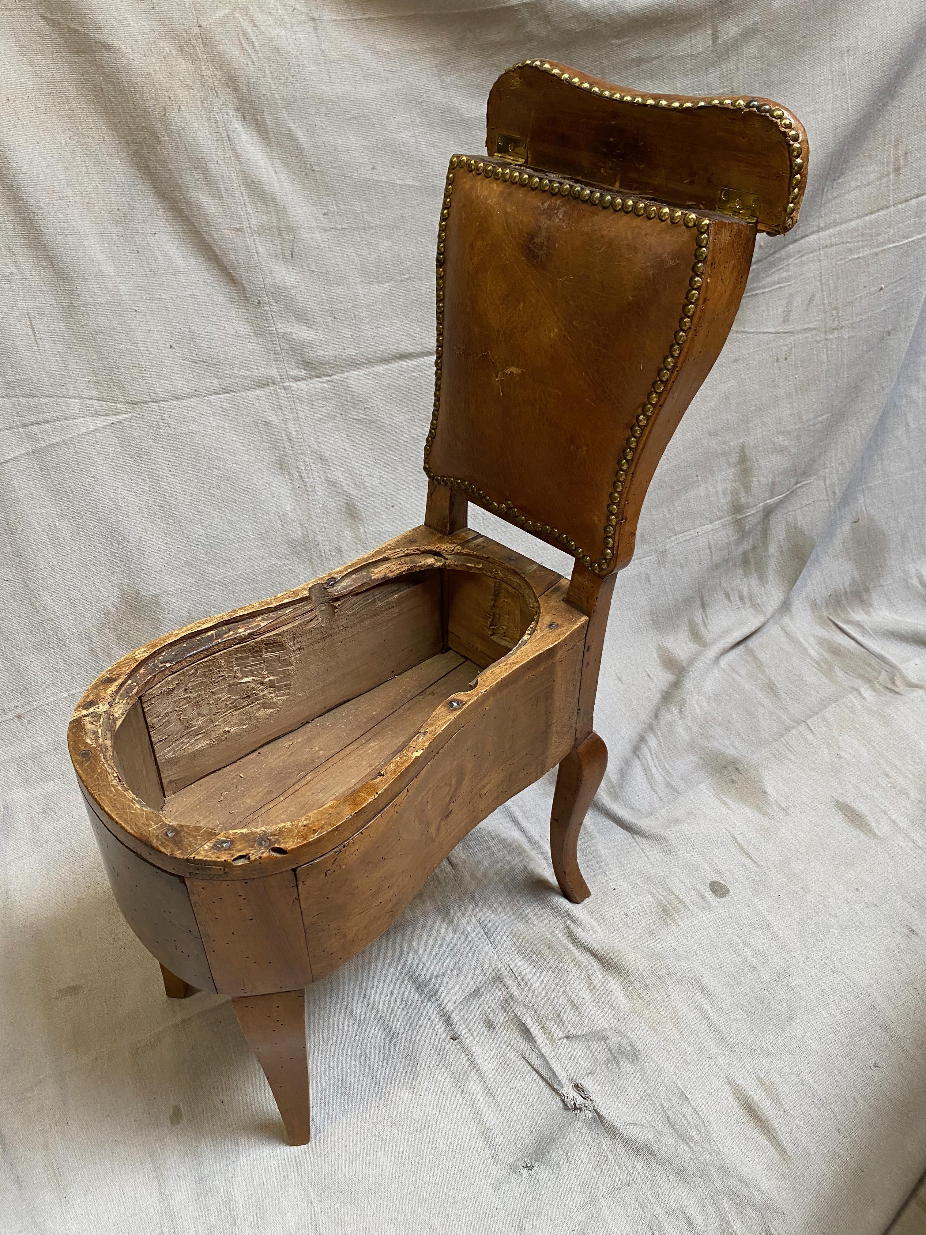 This magnificent piece of history, a French Louis XV-period (18th century) commode chair, meticulously crafted from high-quality beechwood with brass tack-bound leather over back padding. This antique chair has been immaculately preserved and is in