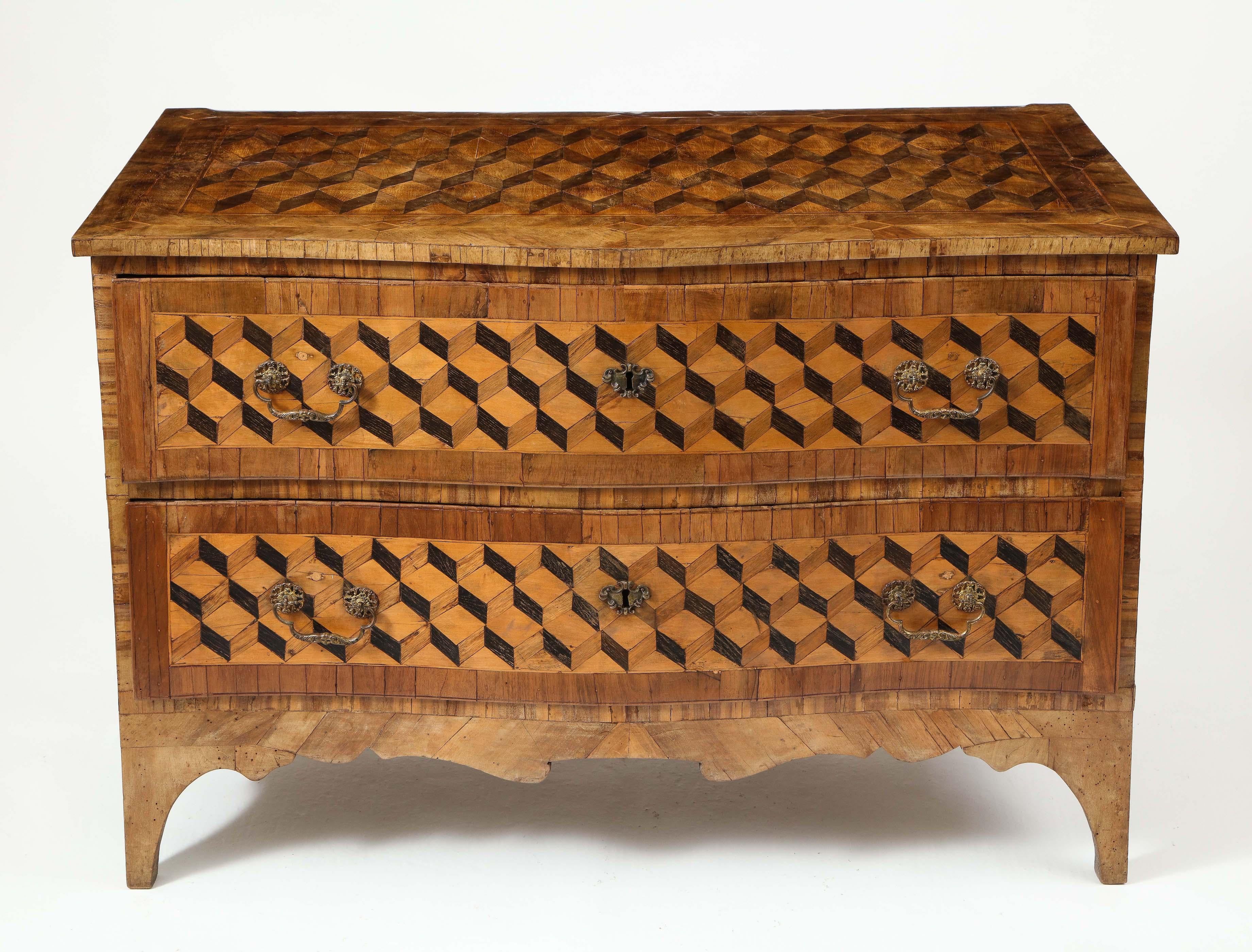 Of serpentine form; with broad walnut banding throughout and inlaid with trompe l'oeil geometric parquetry panels incorporating fruitwood, olive wood, and purpleheart; mounted with silver hardware; fitted with two long drawers mounted with silver