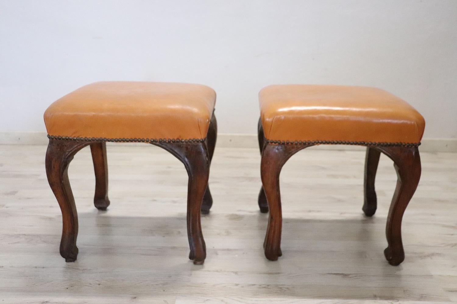 Beautiful and rare pair of 18th century antique stools. Made of walnut wood with light brown leather seat. Featuring sleek, wavy legs. Good condition to report some signs of wear in the leather.