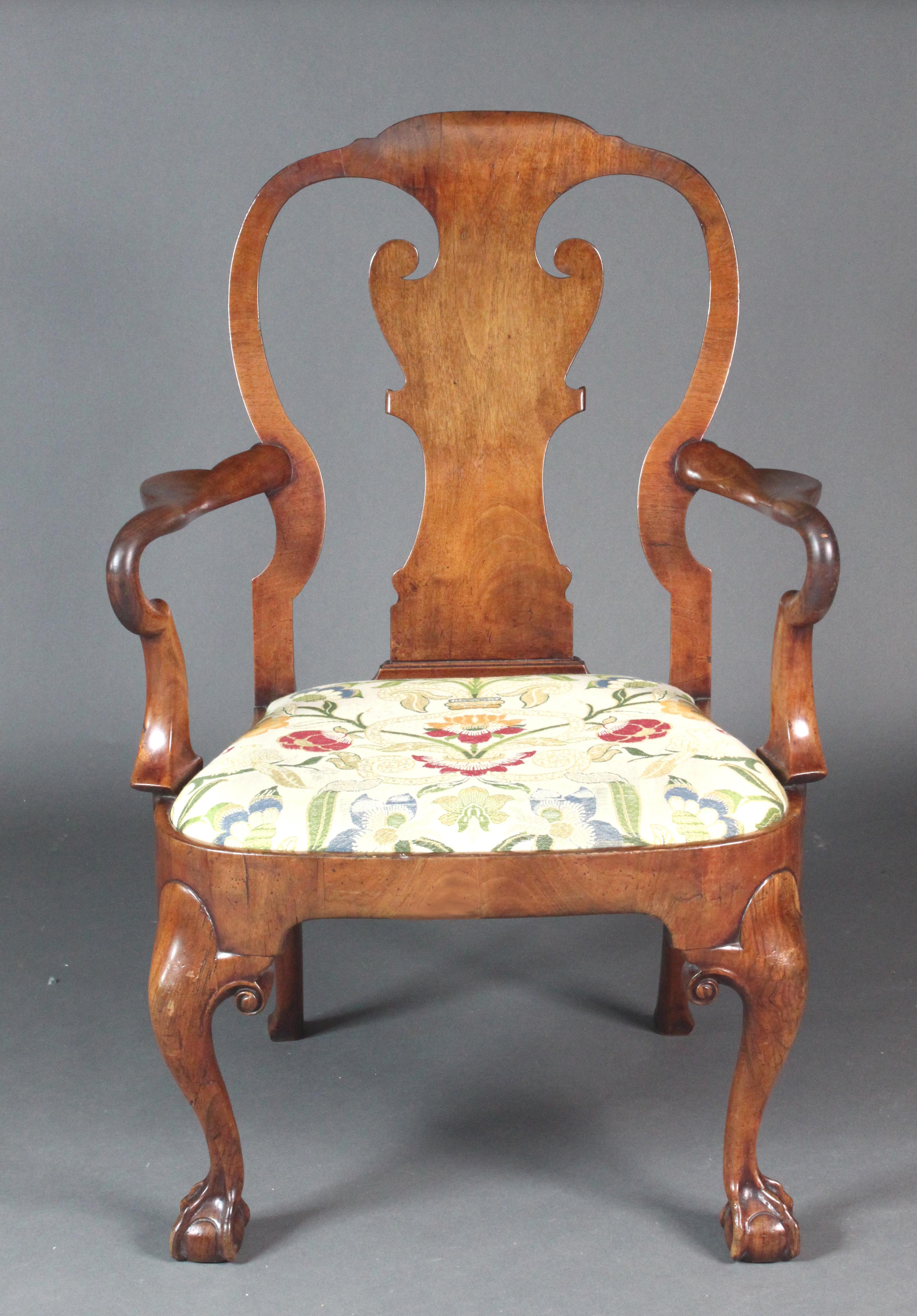 An early 18th Century veneered walnut arm chair on winged cabriole legs with claw feet, shepherd's crook arms and a handsome shaped back splat. Good generous size, original condition with one old repair to one of the legs.