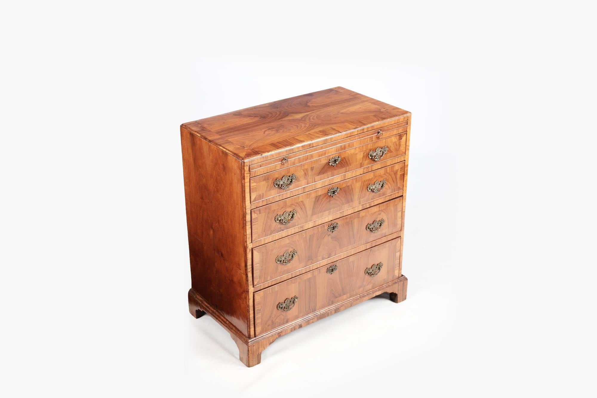 18th Century walnut bachelor's chest with four full drawers and pull-out writing slide and original handles. It is supported on ogee bracket feet.