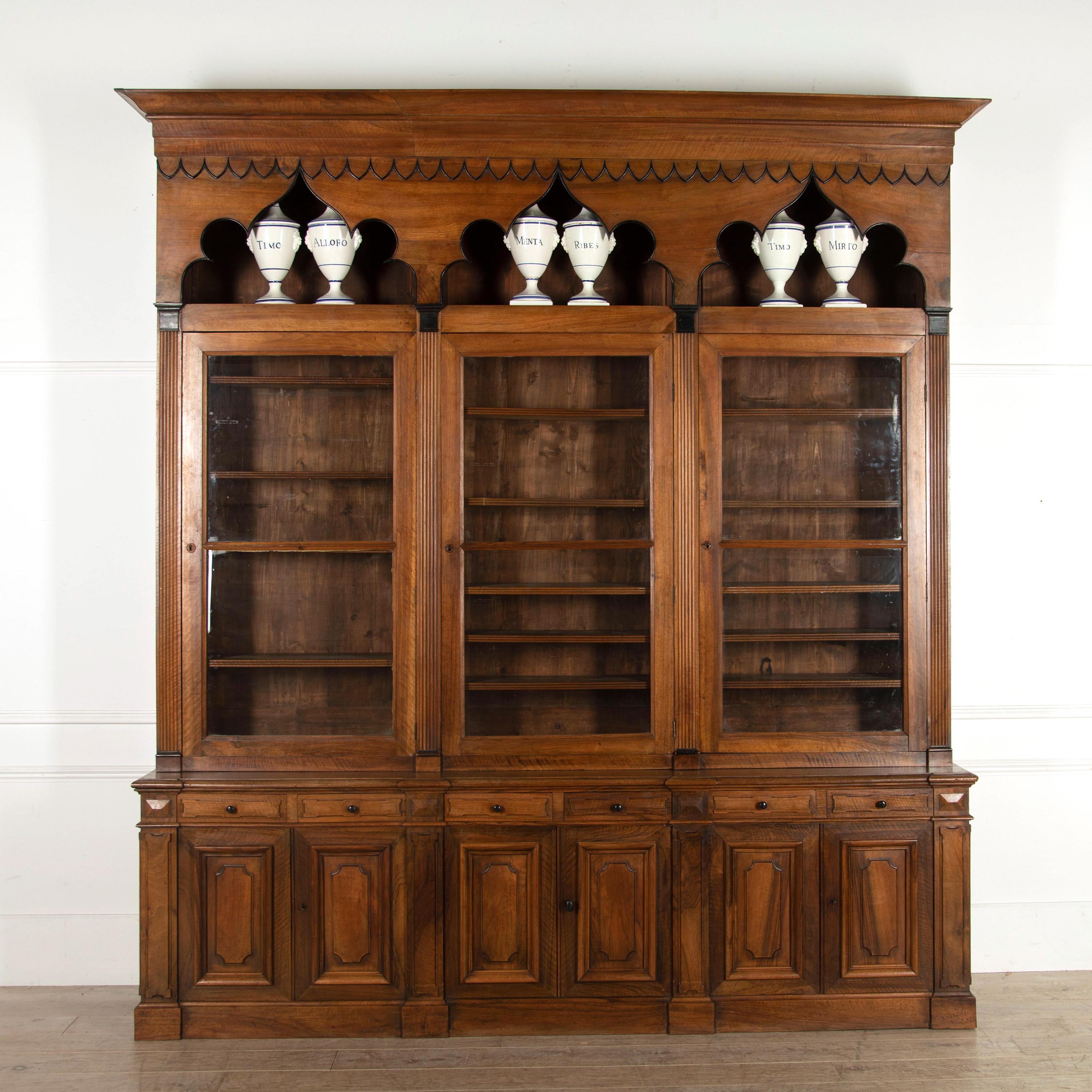 18th century solid walnut gothic style bookcase, stunning example of French craftsmanship. From a Lyon Doctors Hôtel Particulier. Three doors glazed with the original antique glass, and carved bullnose shelving, sits upon the elegant enfilade base