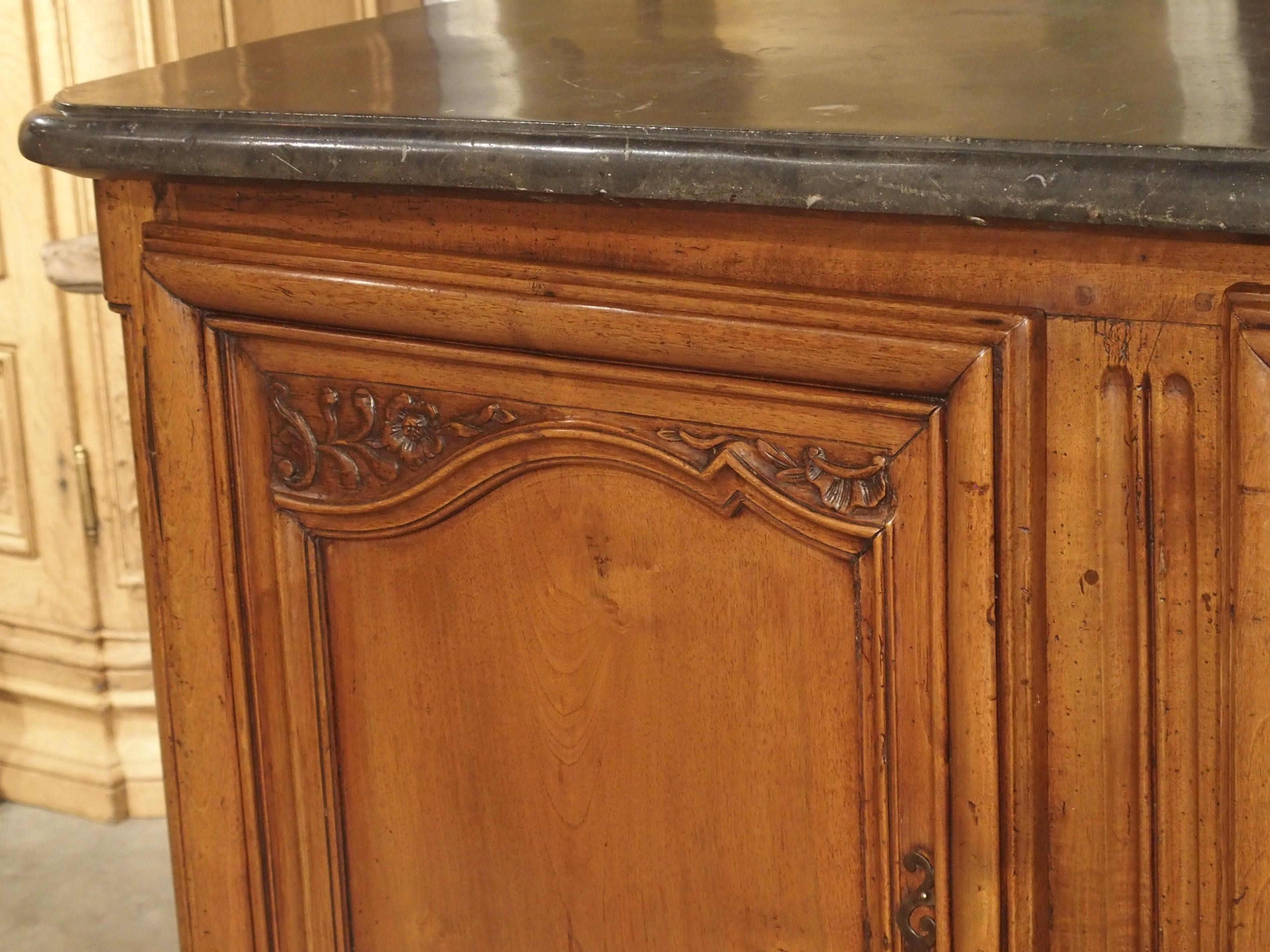 This beautiful walnut buffet de chasse (hunting buffet) is characteristic of furniture from the Rhone-Alpes region of France during the Louis XV period. Topped with a dark gray Saint Cyr stone with marine inclusions, the buffet was hand-carved in
