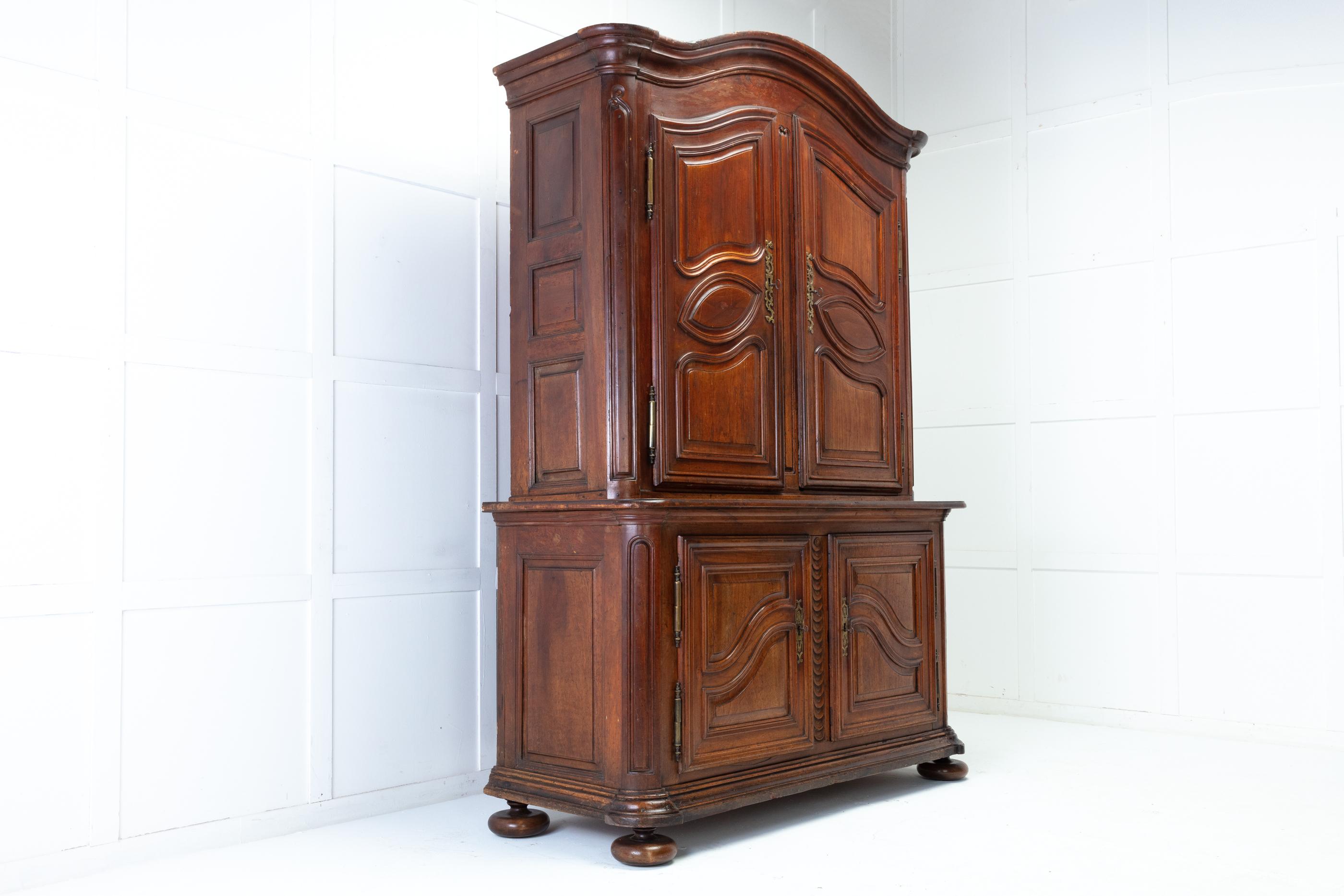 18th century walnut buffet deux corps. Having a deep moulded, arched cornice above a pair of panelled doors with faceted brass hinges that open to reveal two shelves on either side. The low waisted base has a further two panelled doors that reveal a