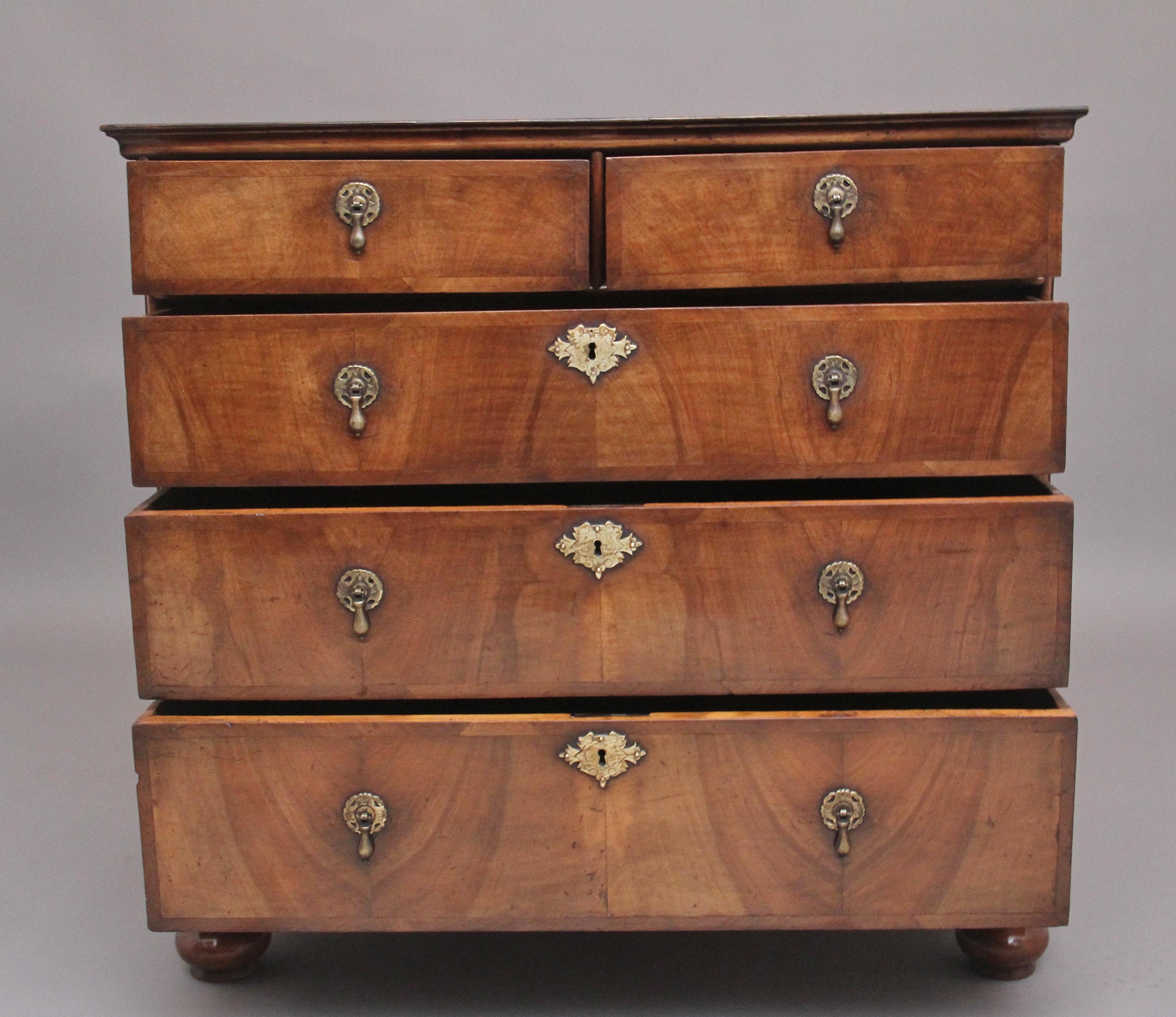 18th century walnut chest of drawers, having a wonderfully figured and crossbanded top with a moulded edge above two short over three oak lined graduated drawers with brass drop handles and escutcheons, standing on elegant turned feet. Lovely walnut
