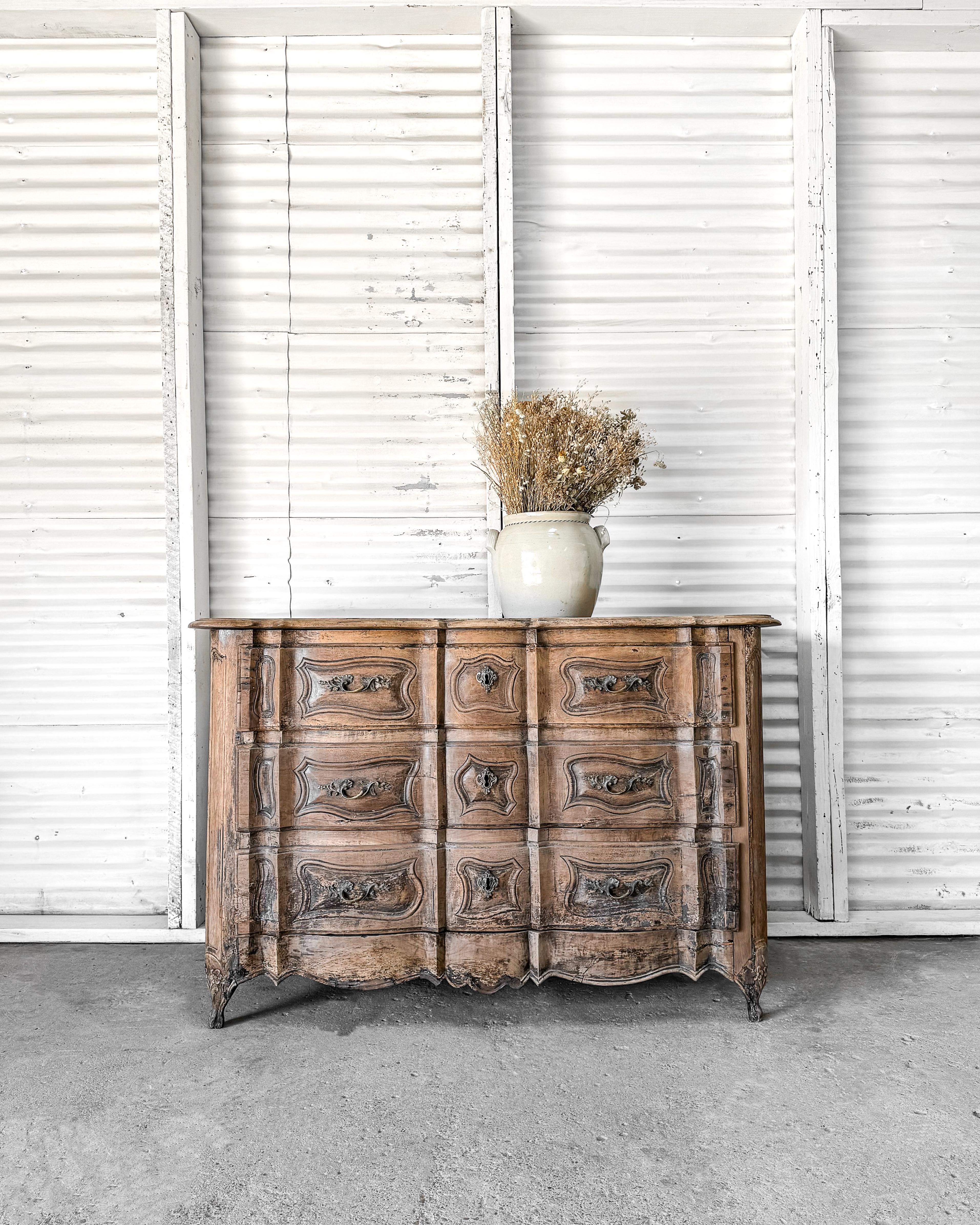A beautiful French Provincial 3-drawer walnut commode with serpentine front and conforming molded edge 2-board top. Carved details at the shaped drawers, side paneling, and corner posts enhance the design. Original foliate brass hardware adorns the