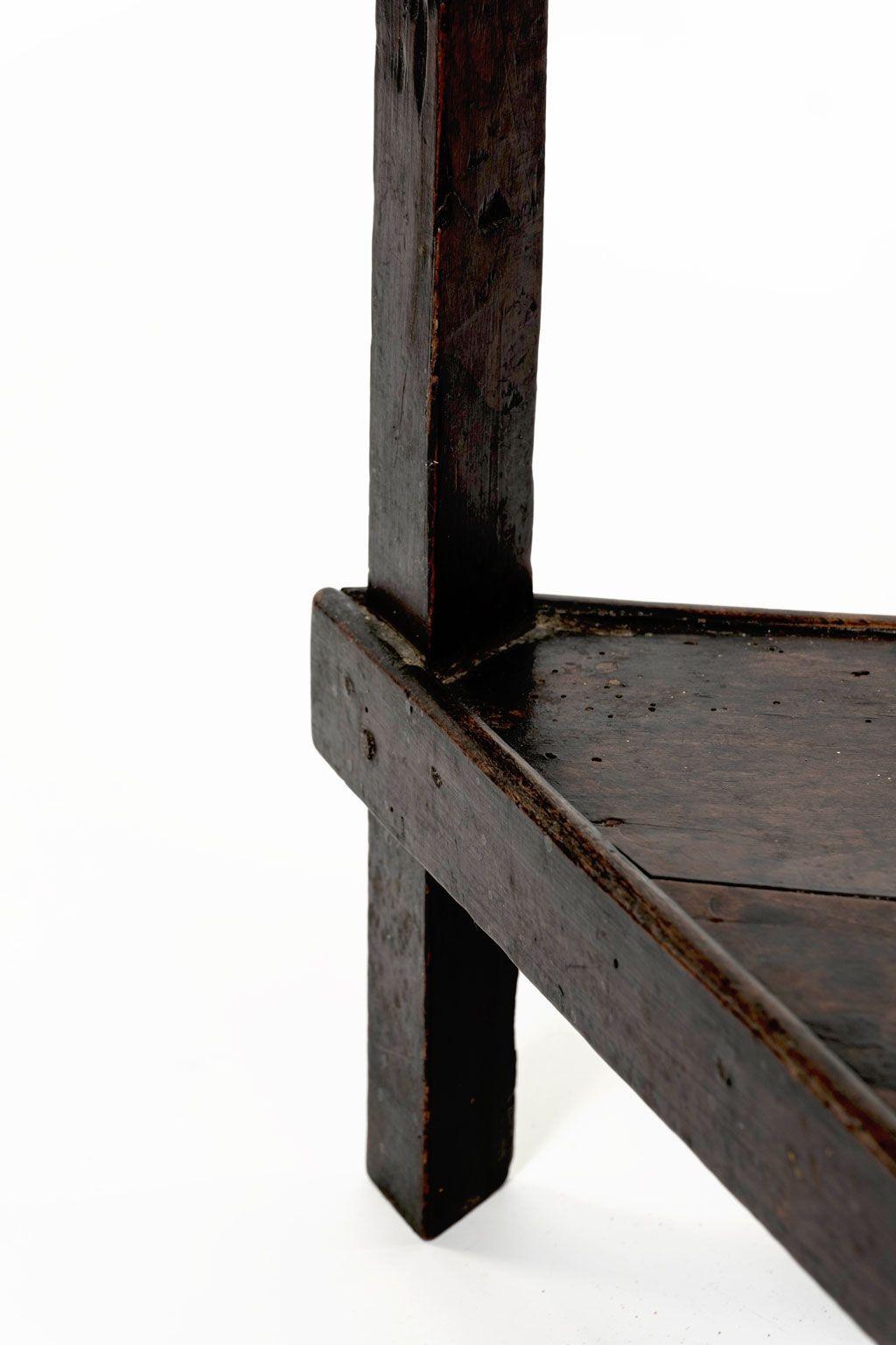 Table de grillon en noyer du XVIIIe siècle : plateau ovale sur trois supports triangulaires à facettes réunis par une étagère triangulaire sous le plateau. Des consoles en fer forgé et martelé sont appliquées aux coins du tablier, sous le plateau.