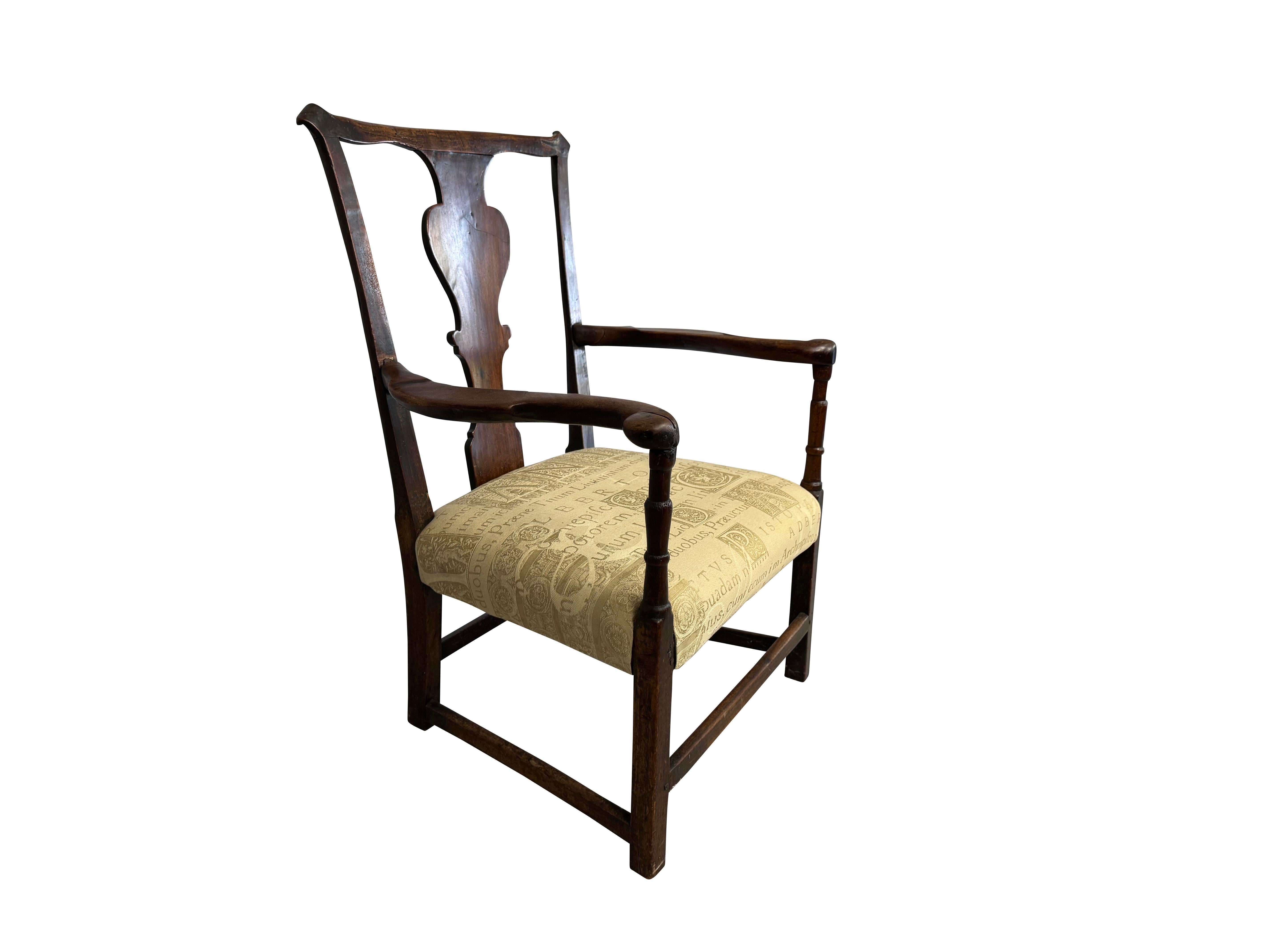 Ein antiker Holzsessel mit charakteristischen Merkmalen der Epoche
Der Stuhl scheint aus dem 18. Jahrhundert zu stammen, wahrscheinlich aus der georgianischen oder Queen-Anne-Periode, basierend auf seinen Designelementen. Er verfügt über eine